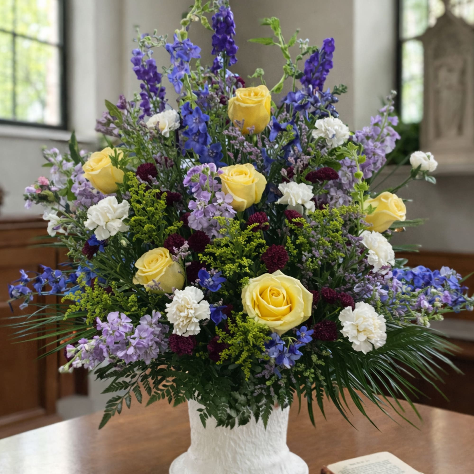 A timeless, one-sided funeral arrangement thoughtfully designed using the freshest seasonal flowers