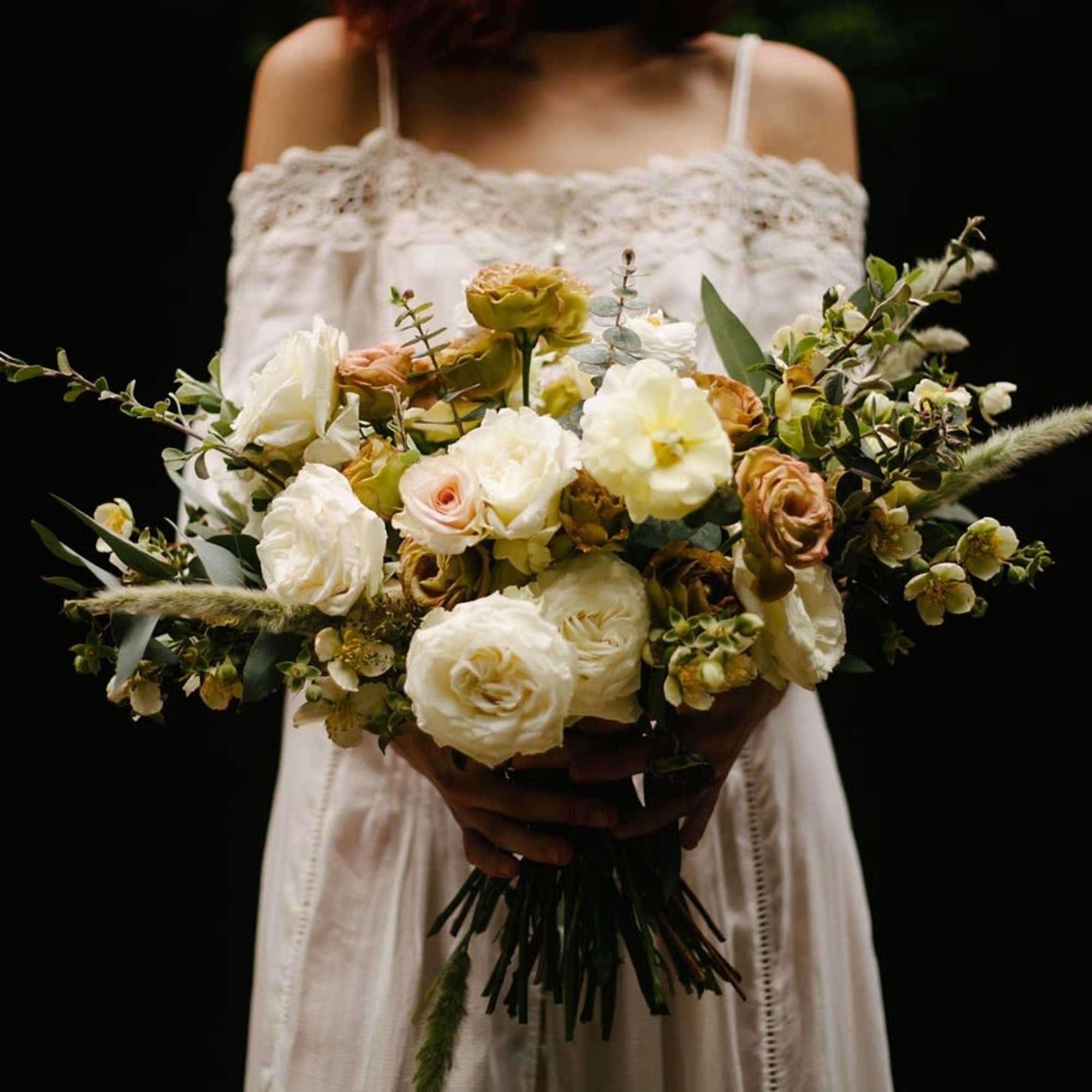 Bride holding a large bouquet of white and blush flowers