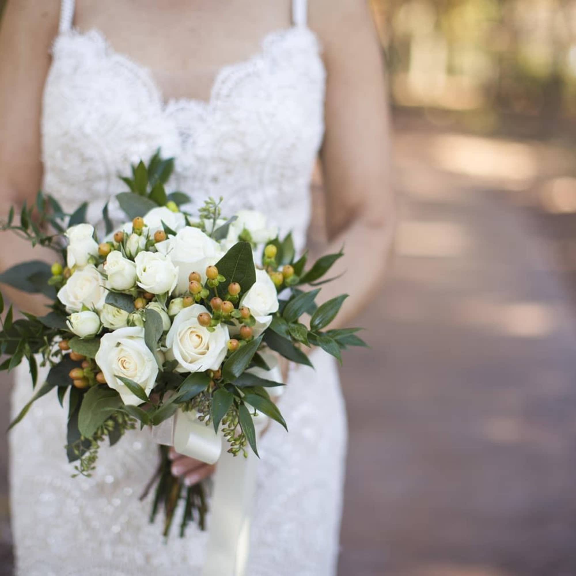 Bride holding a white rose bouquet with greenery