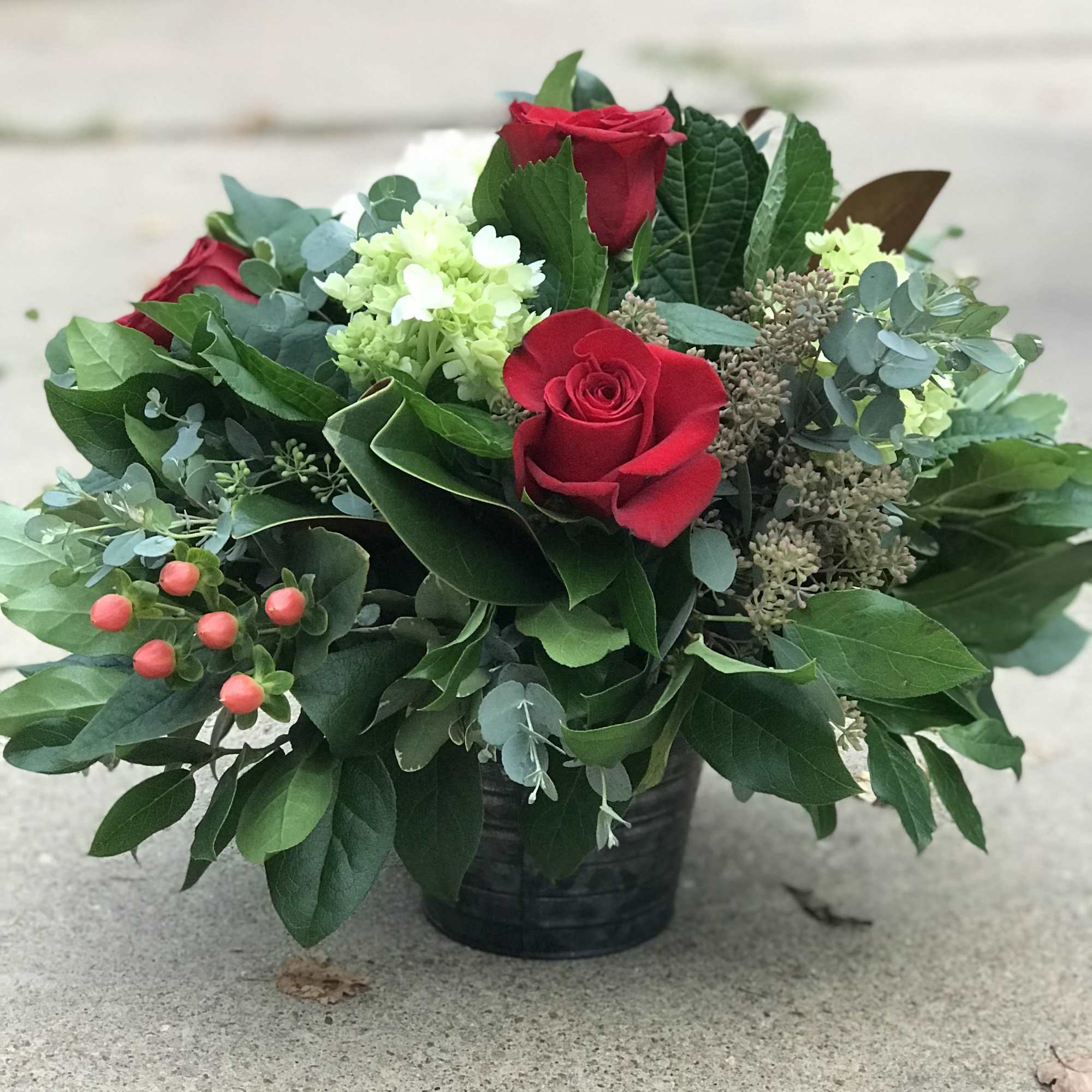 Red roses and pale green blooms in a black container