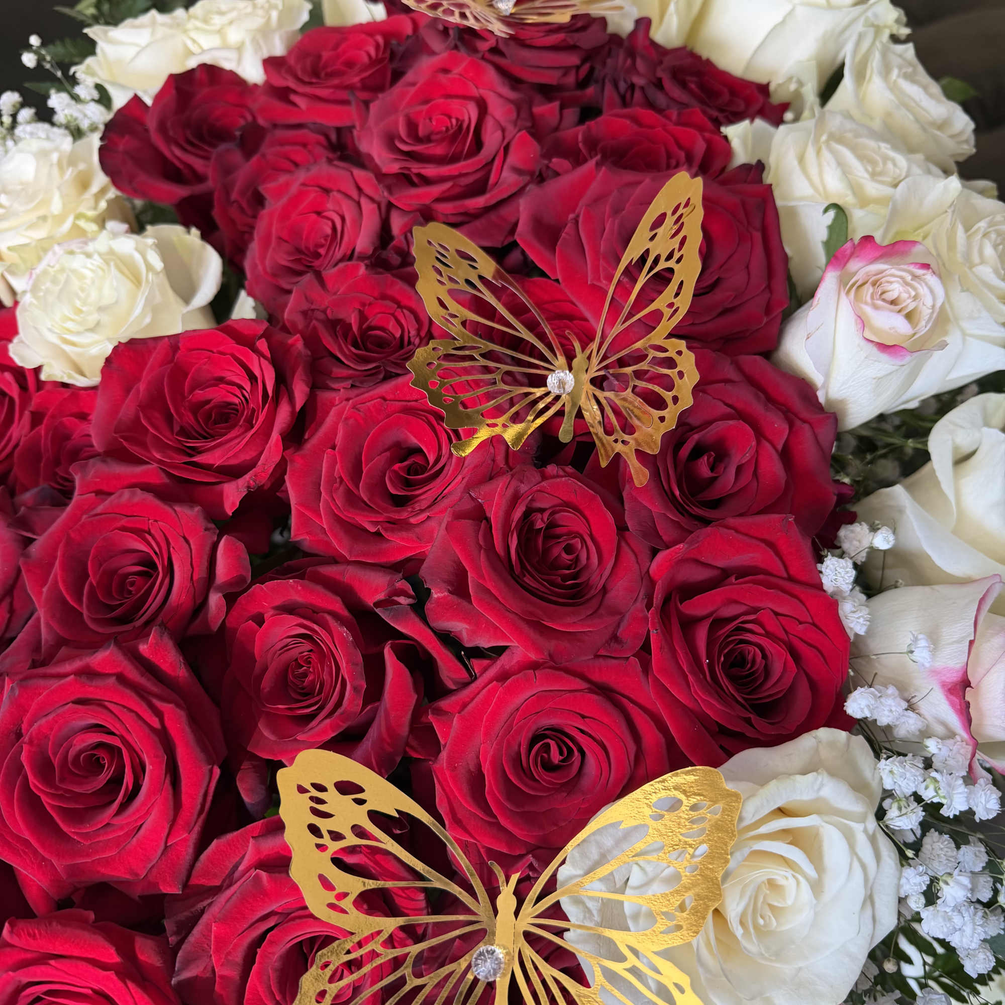 Red and white rose bouquet with gold butterfly decorations