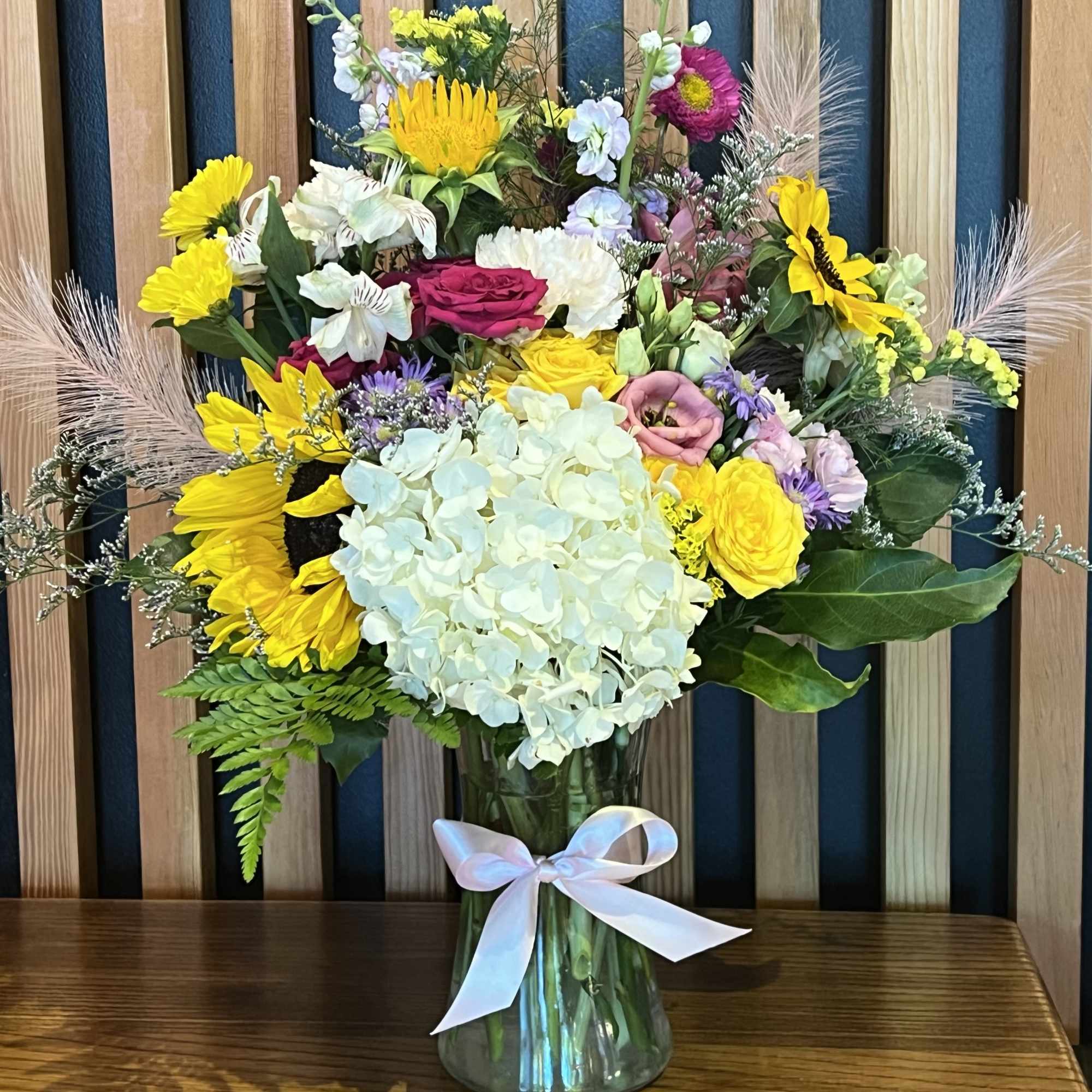 Mixed bouquet in a glass vase with a white ribbon