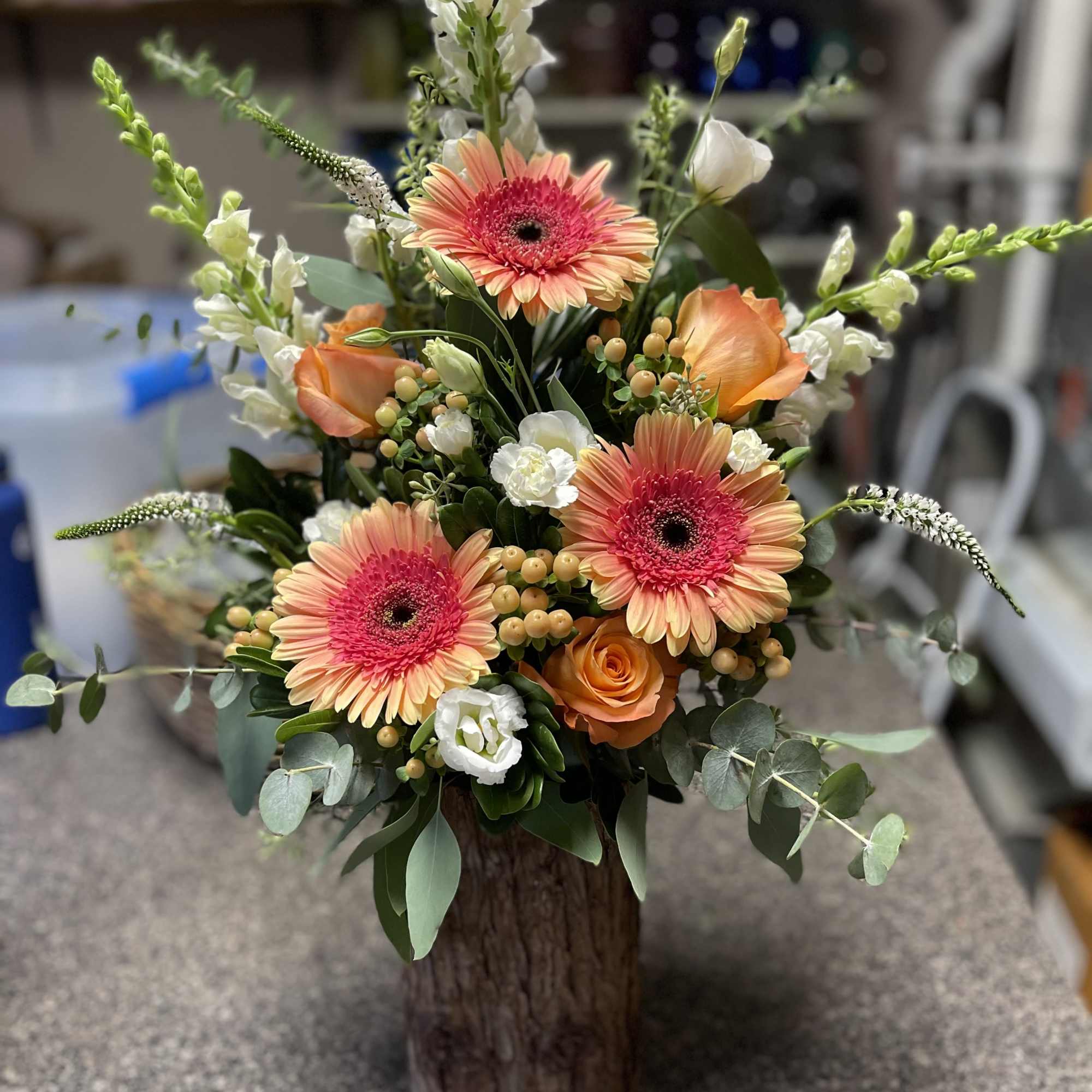 Orange gerbera daisies and roses in a rustic wooden container