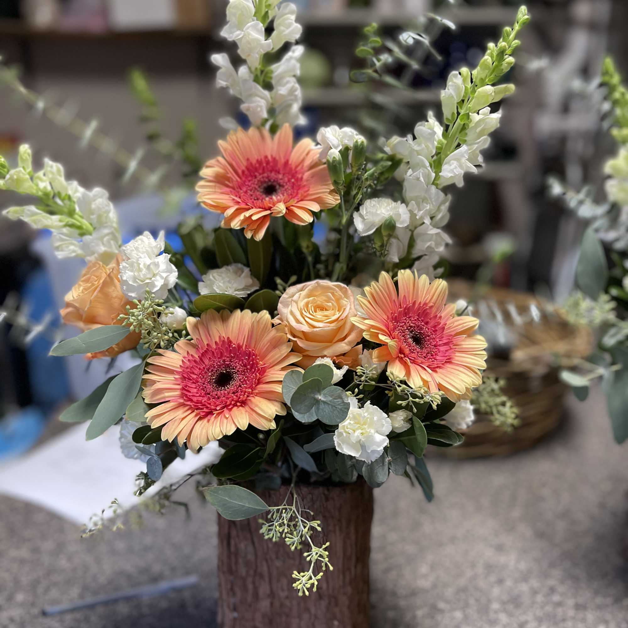 Bouquet of peach gerbera daisies and roses in a wooden vase