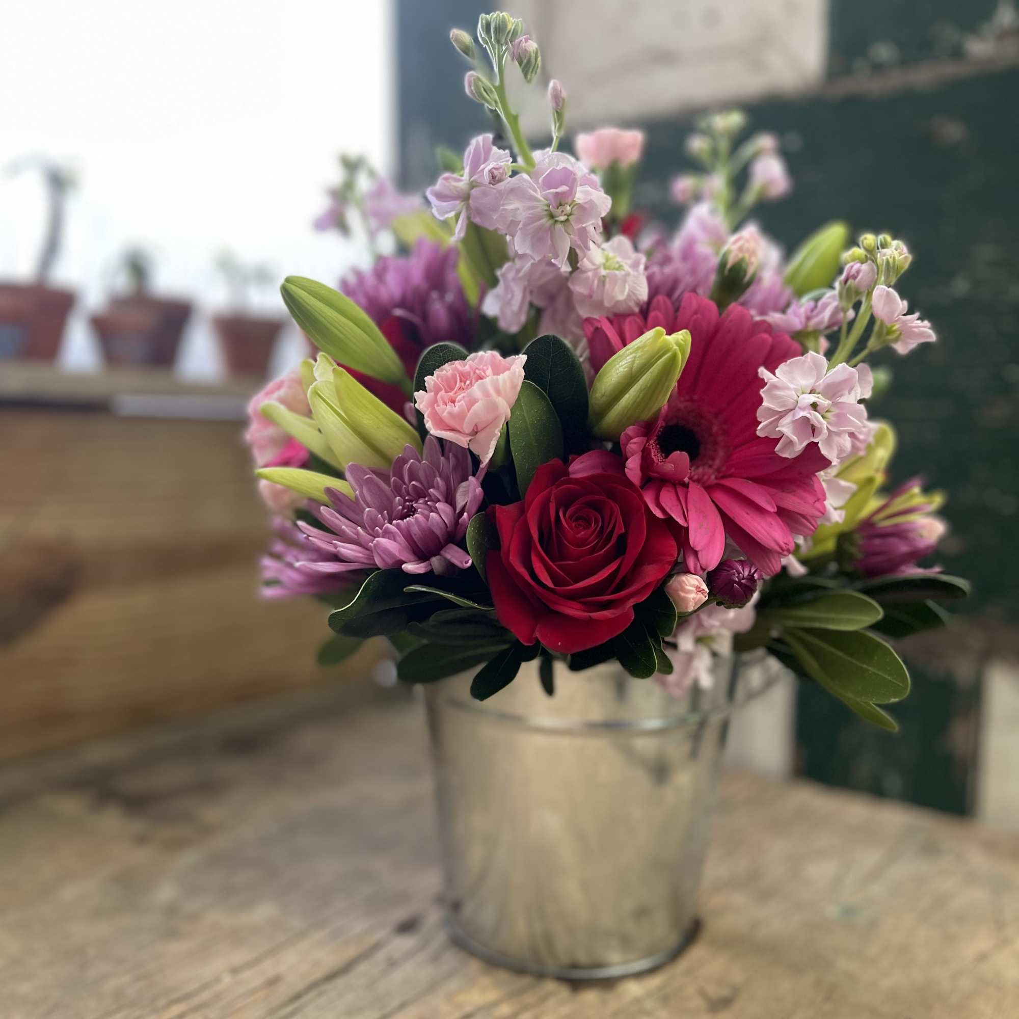 Mixed pink and purple bouquet in a metal bucket vase