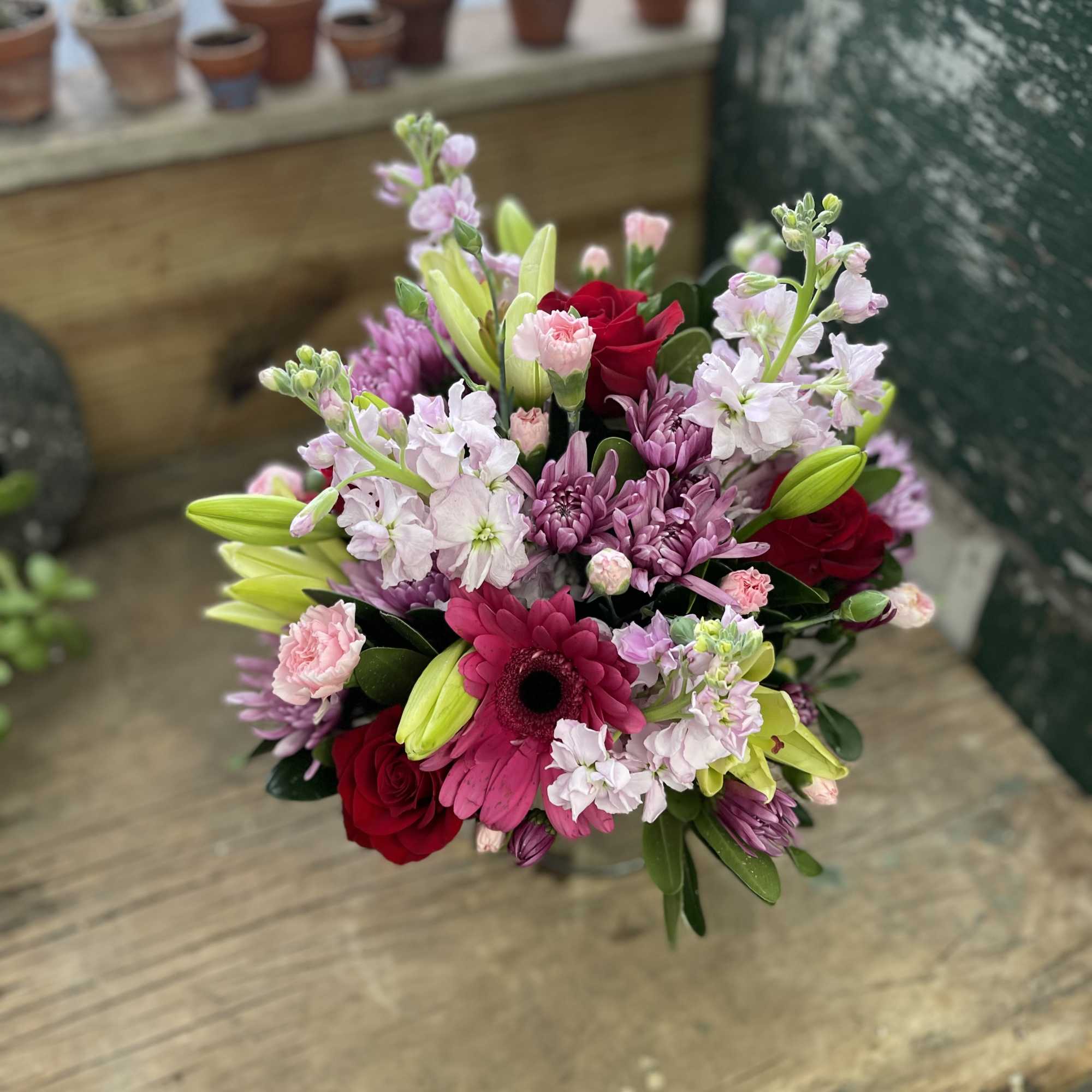 Mixed bouquet with red roses, pink gerbera, lilies, and lavender blooms