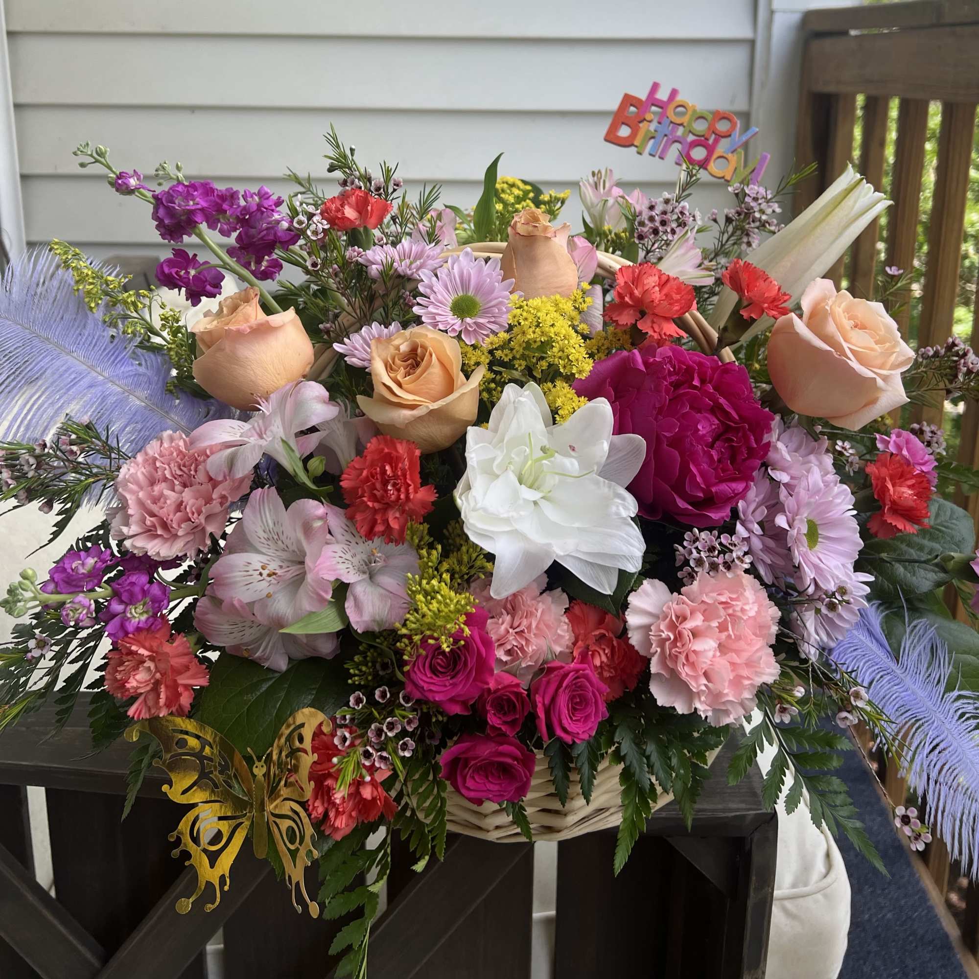 Mixed bouquet in a wicker basket with roses, carnations, daisies, and a birthday sign