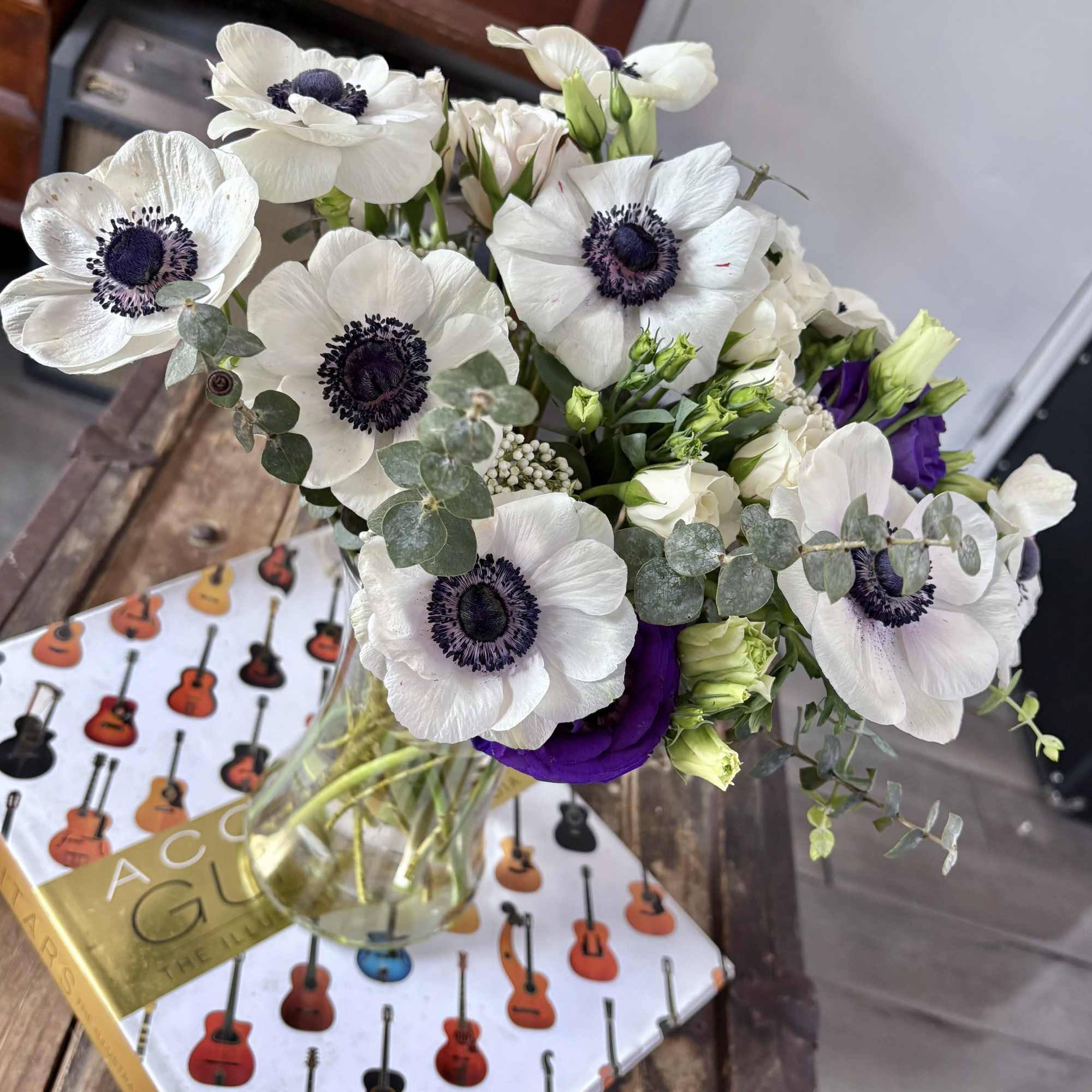 This exquisite arrangement features striking anemones alongside lush textures of eucalyptus and