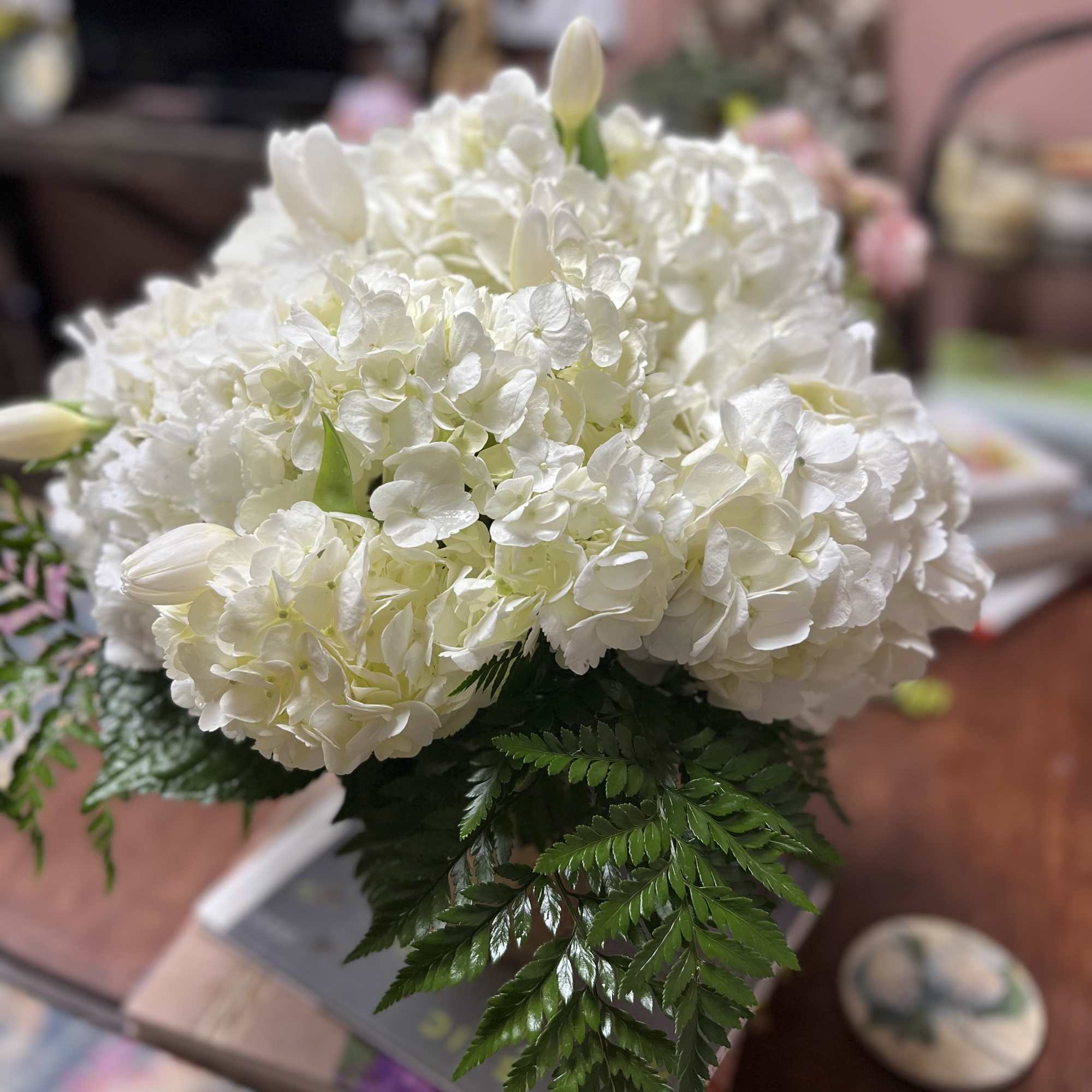 White hydrangea bouquet with a few tulip buds and fern foliage