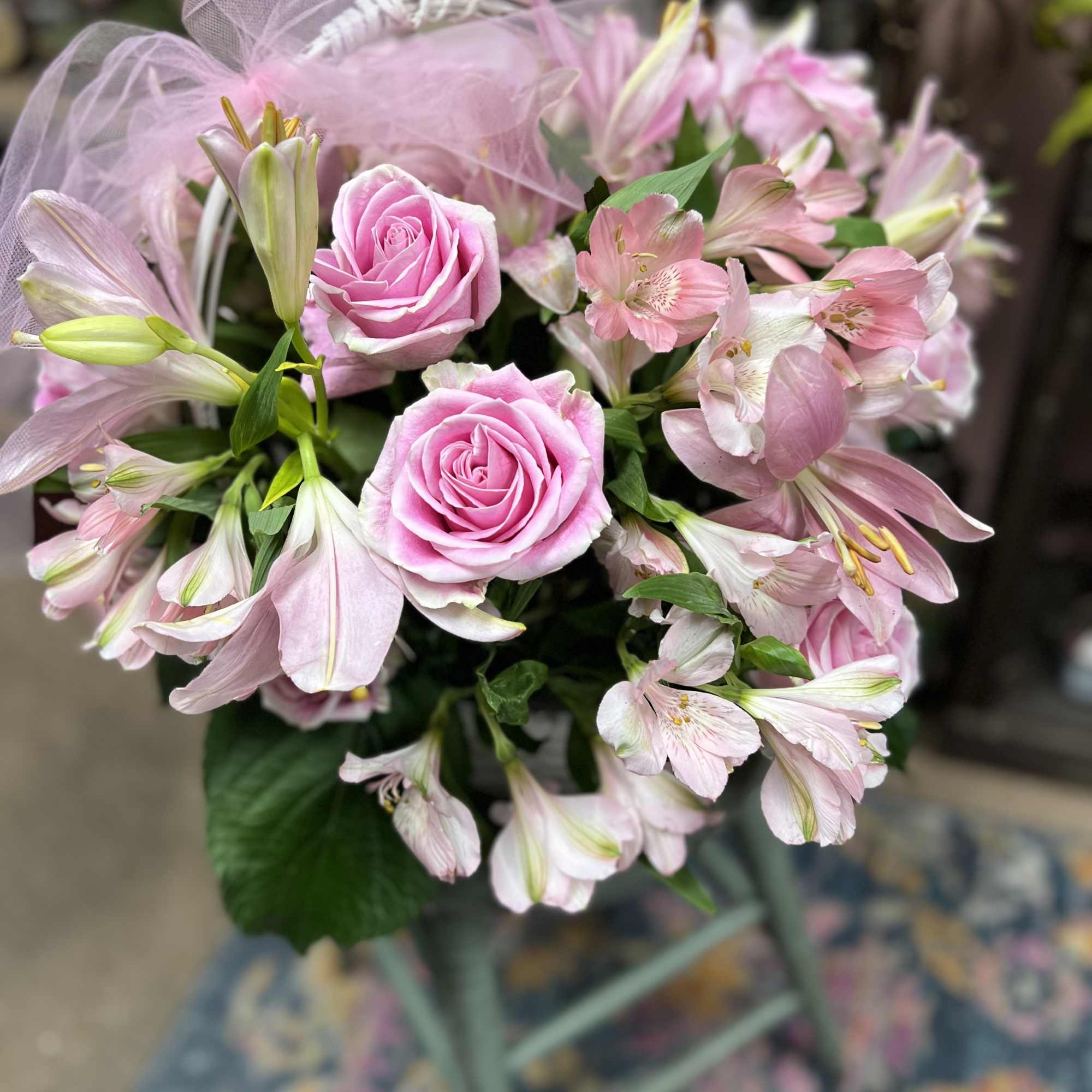 Pink roses and lilies arranged in a bouquet with sheer pink wrap