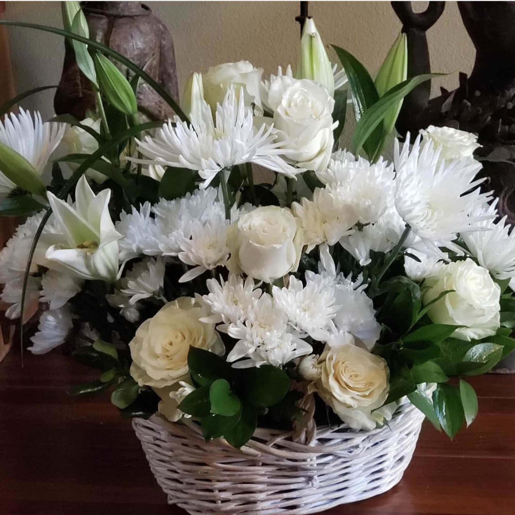 White roses and daisy-like flowers in a wicker basket