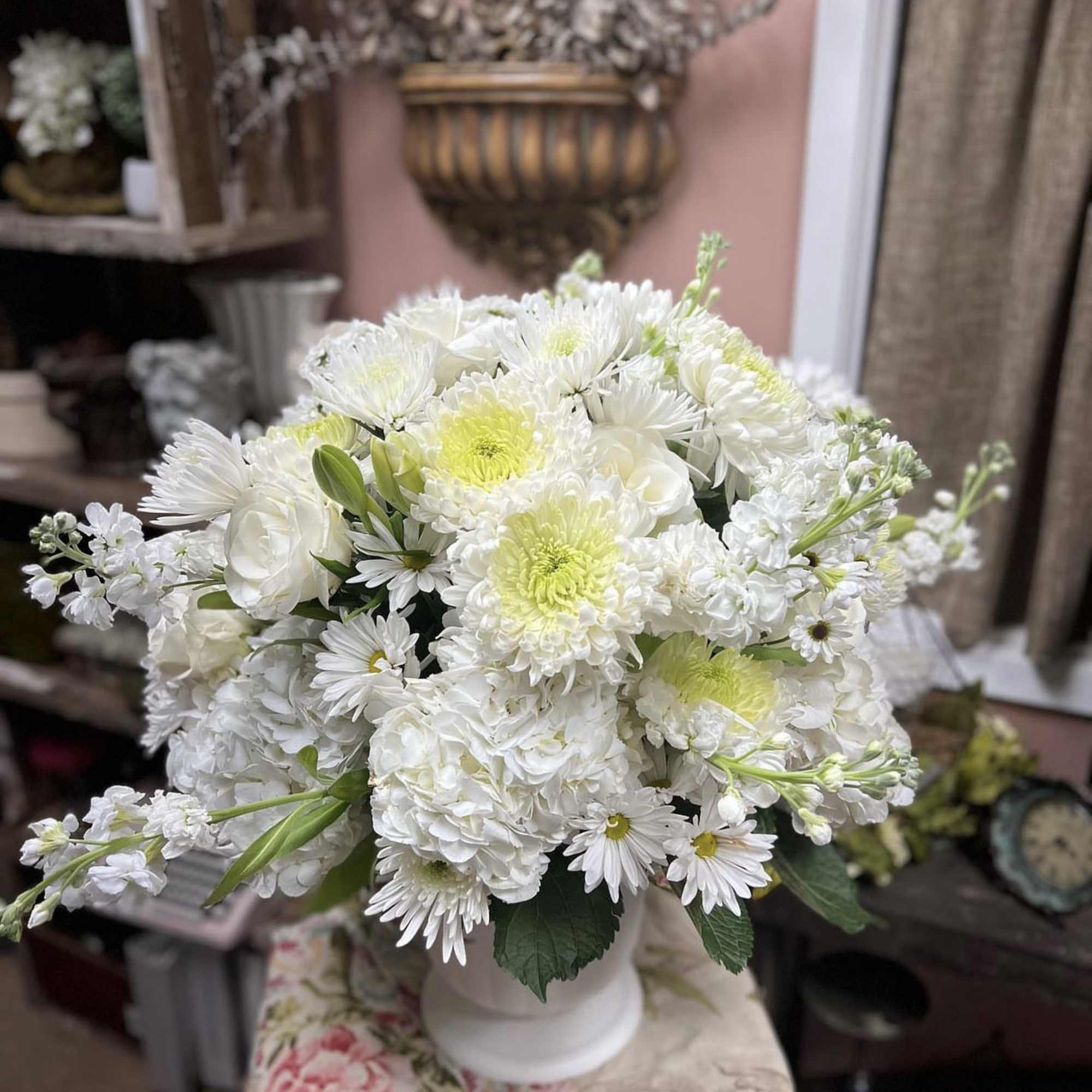 White floral arrangement in a white vase with pale green centers
