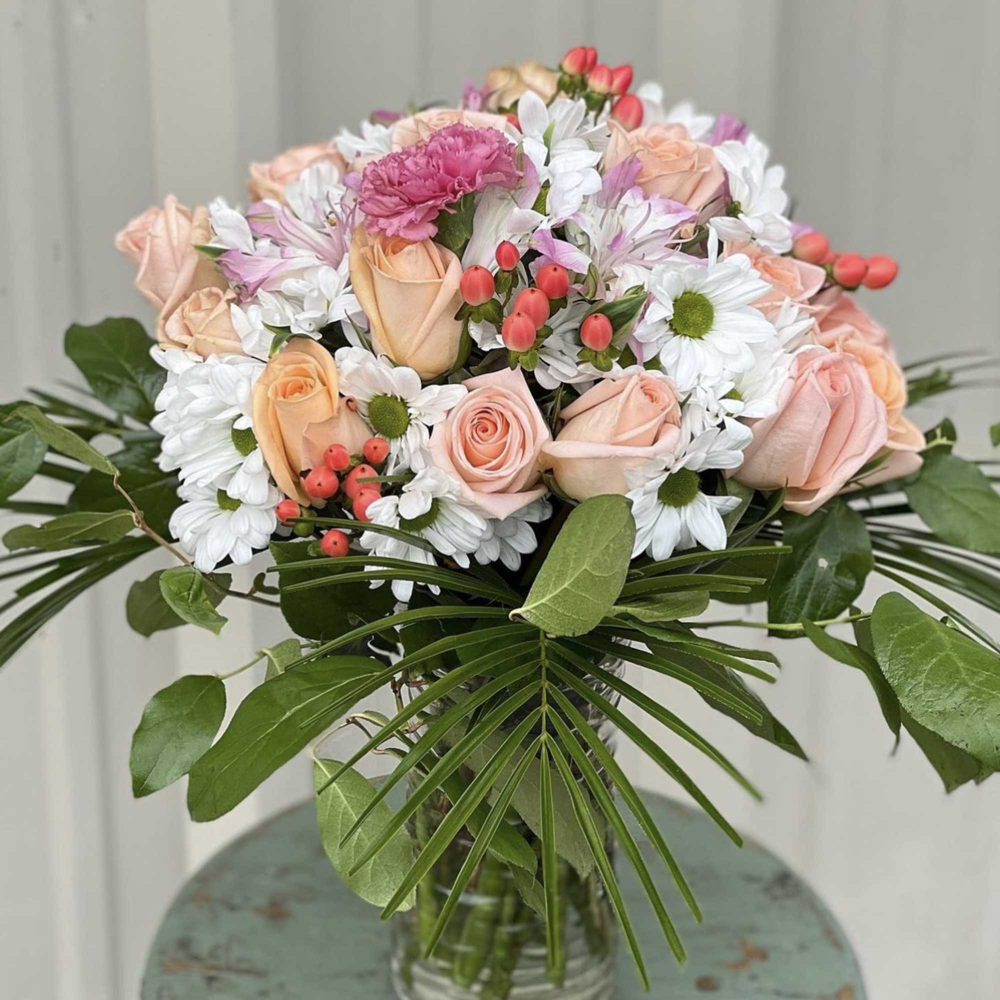 Bouquet of peach roses and white daisies in a glass vase
