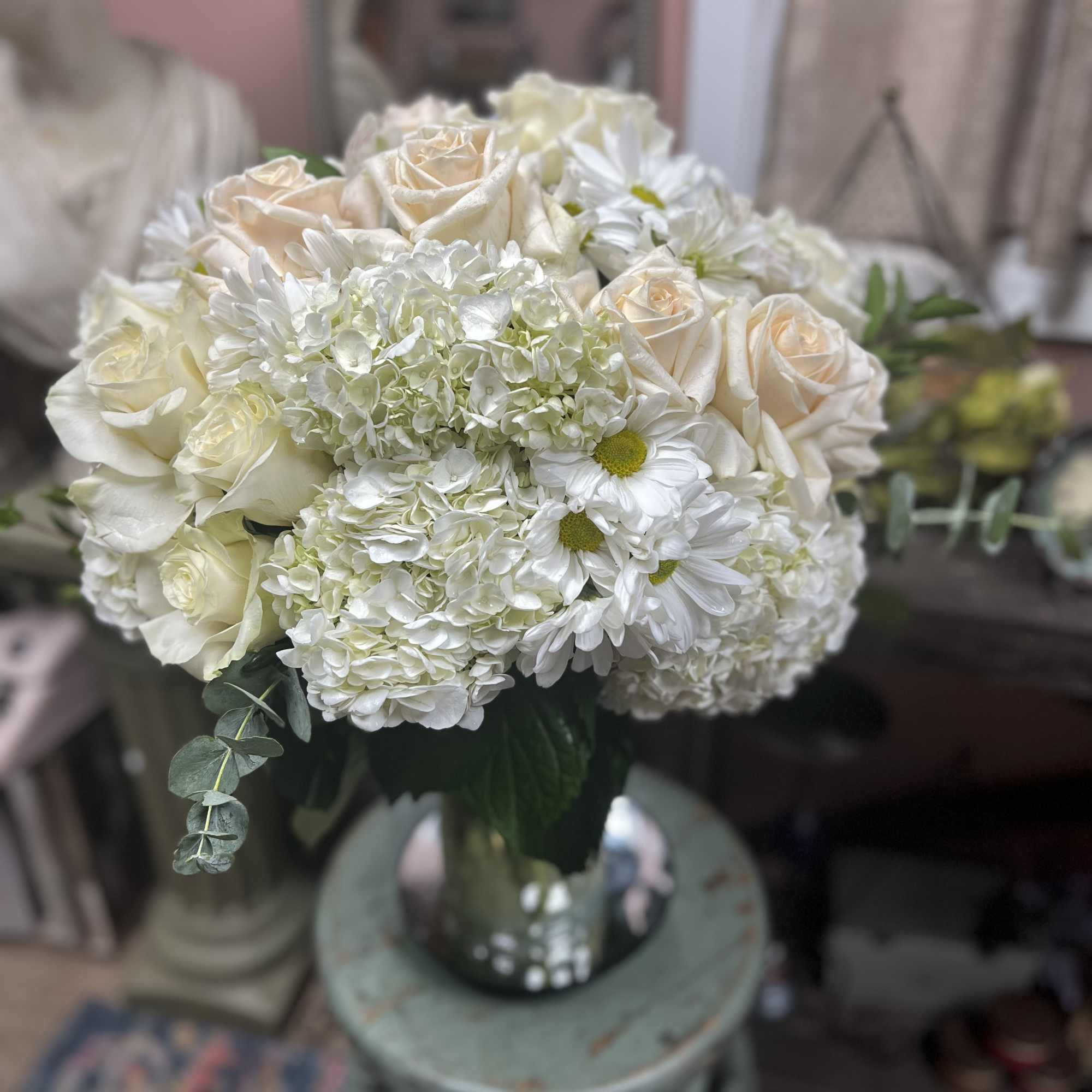 White and cream bouquet of roses, hydrangeas, and daisies in a glass vase