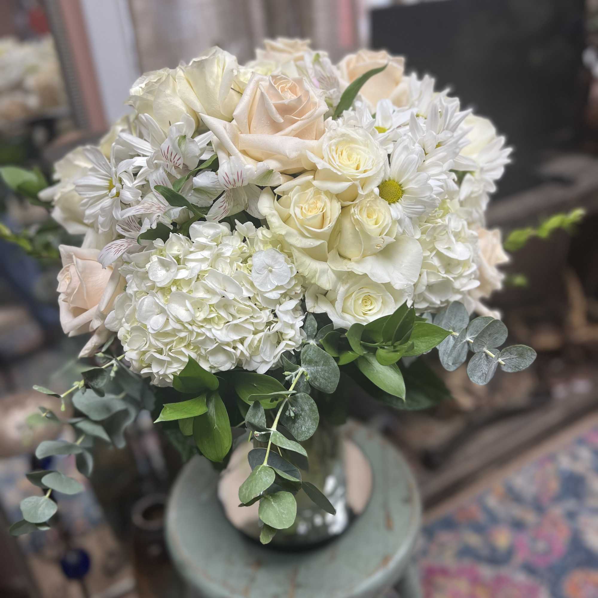Bouquet of white and blush roses with daisies in a glass vase