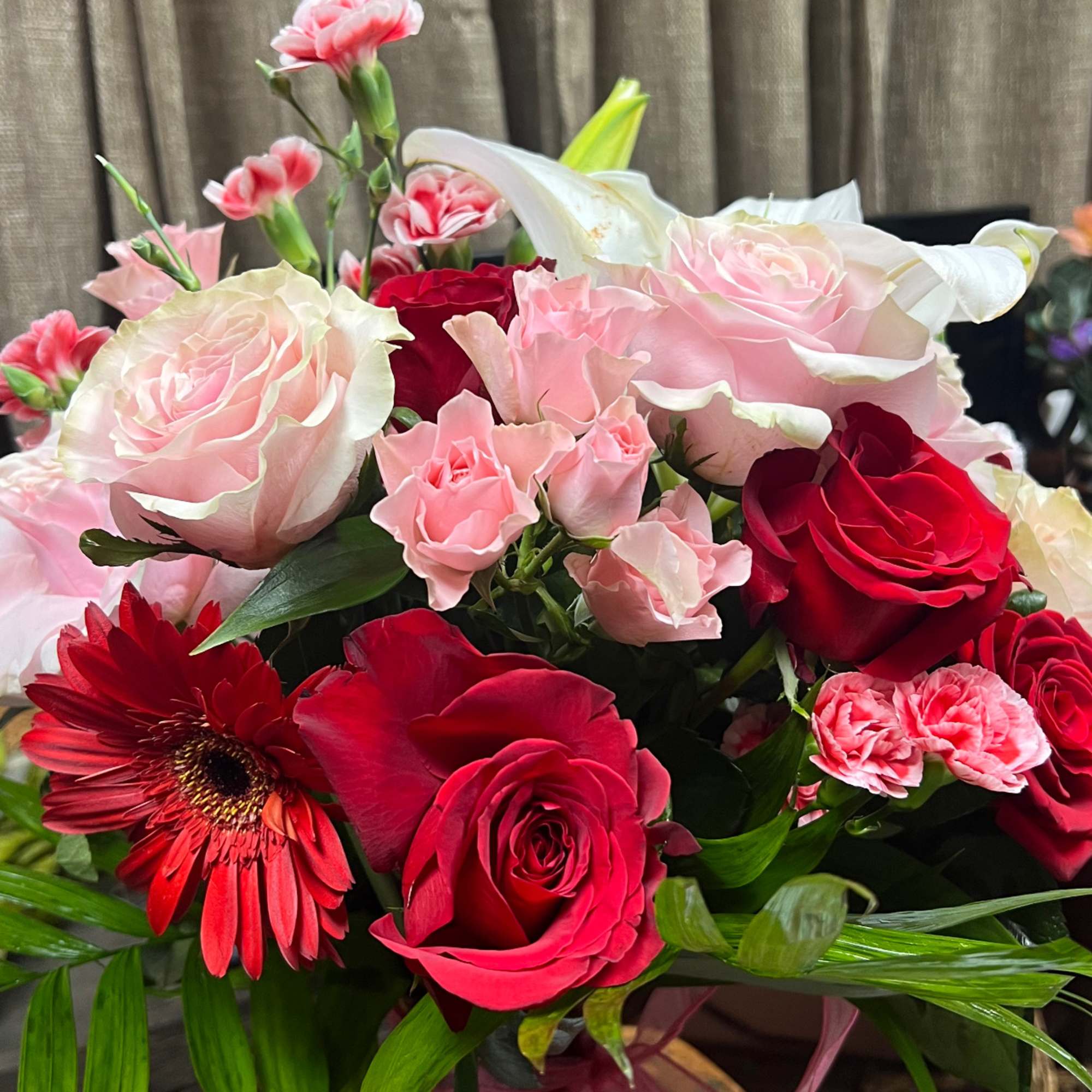 Bouquet of red and pink roses with lilies and gerbera daisies in a vase