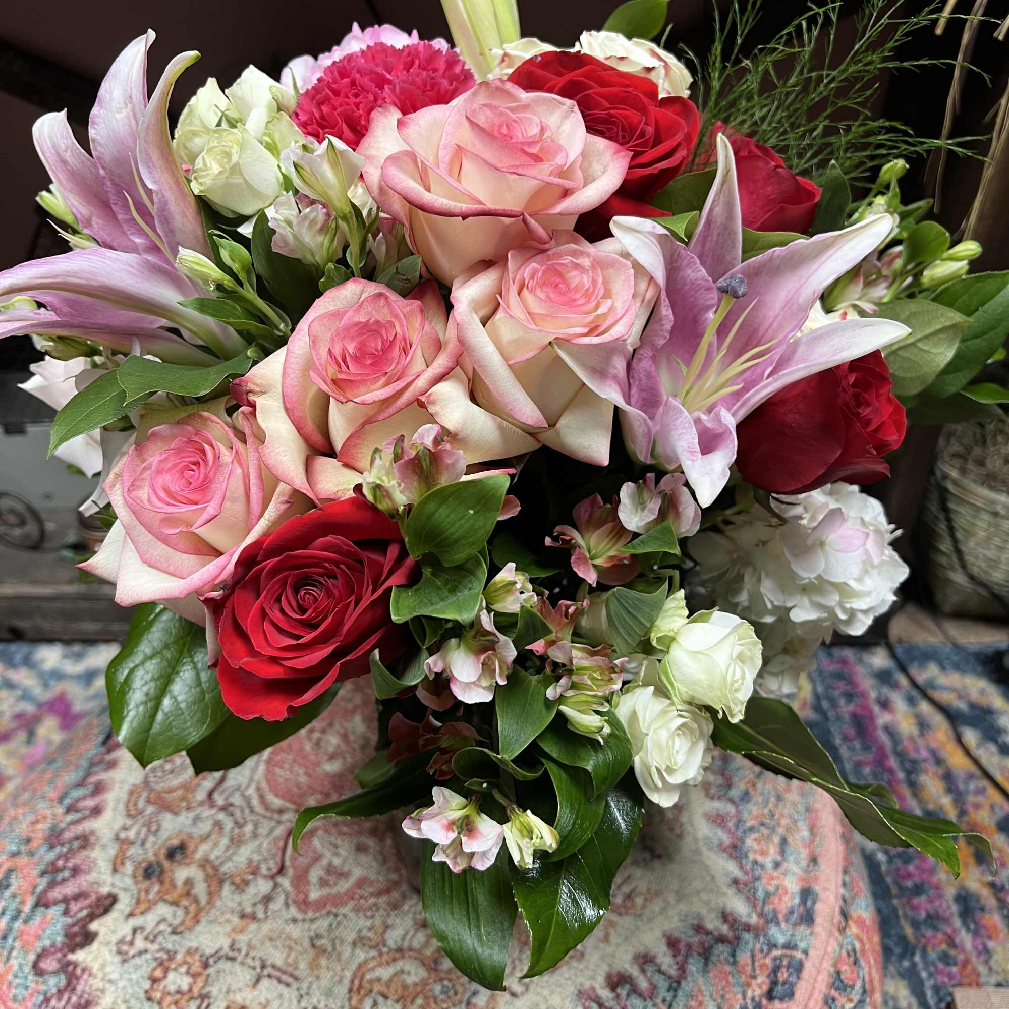Bouquet of pink and red roses with lilies and white filler flowers