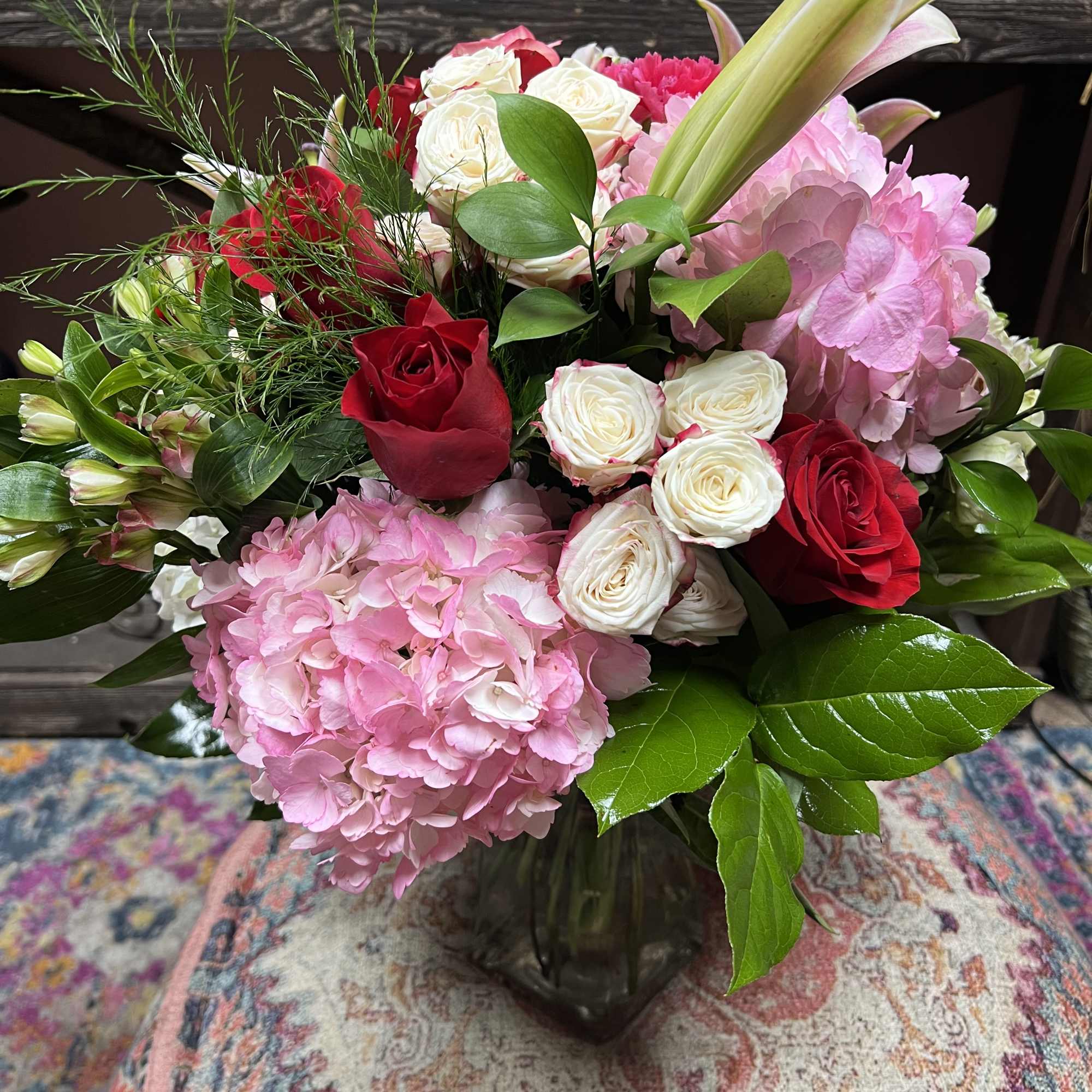 Bouquet of red and white roses with pink hydrangeas in a glass vase