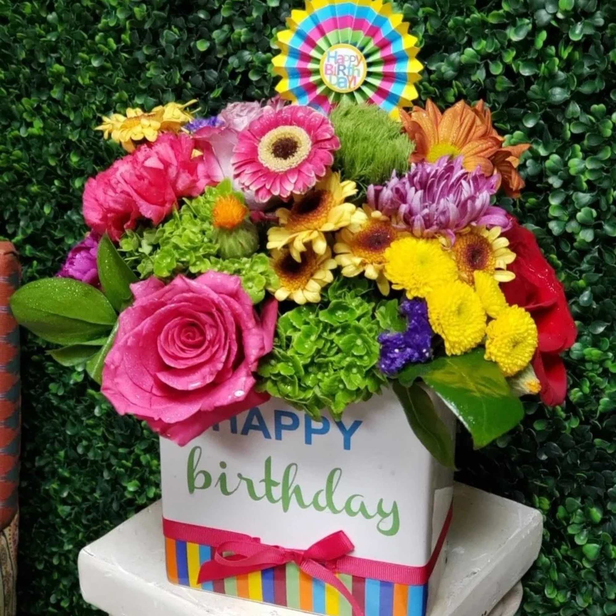 Colorful birthday flower arrangement in a gift box with a rosette topper