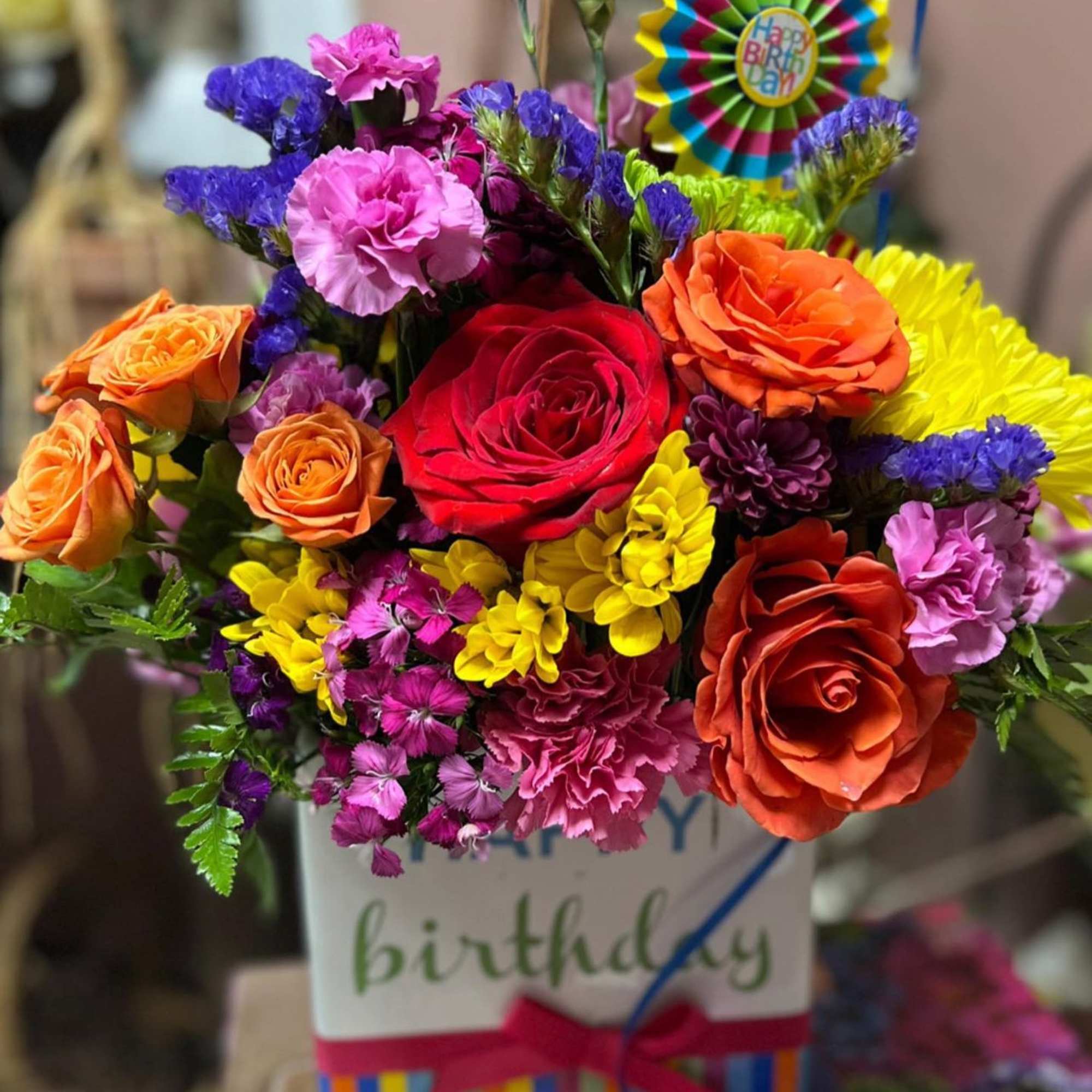 Colorful birthday bouquet in a striped gift box with a "Happy Birthday" topper