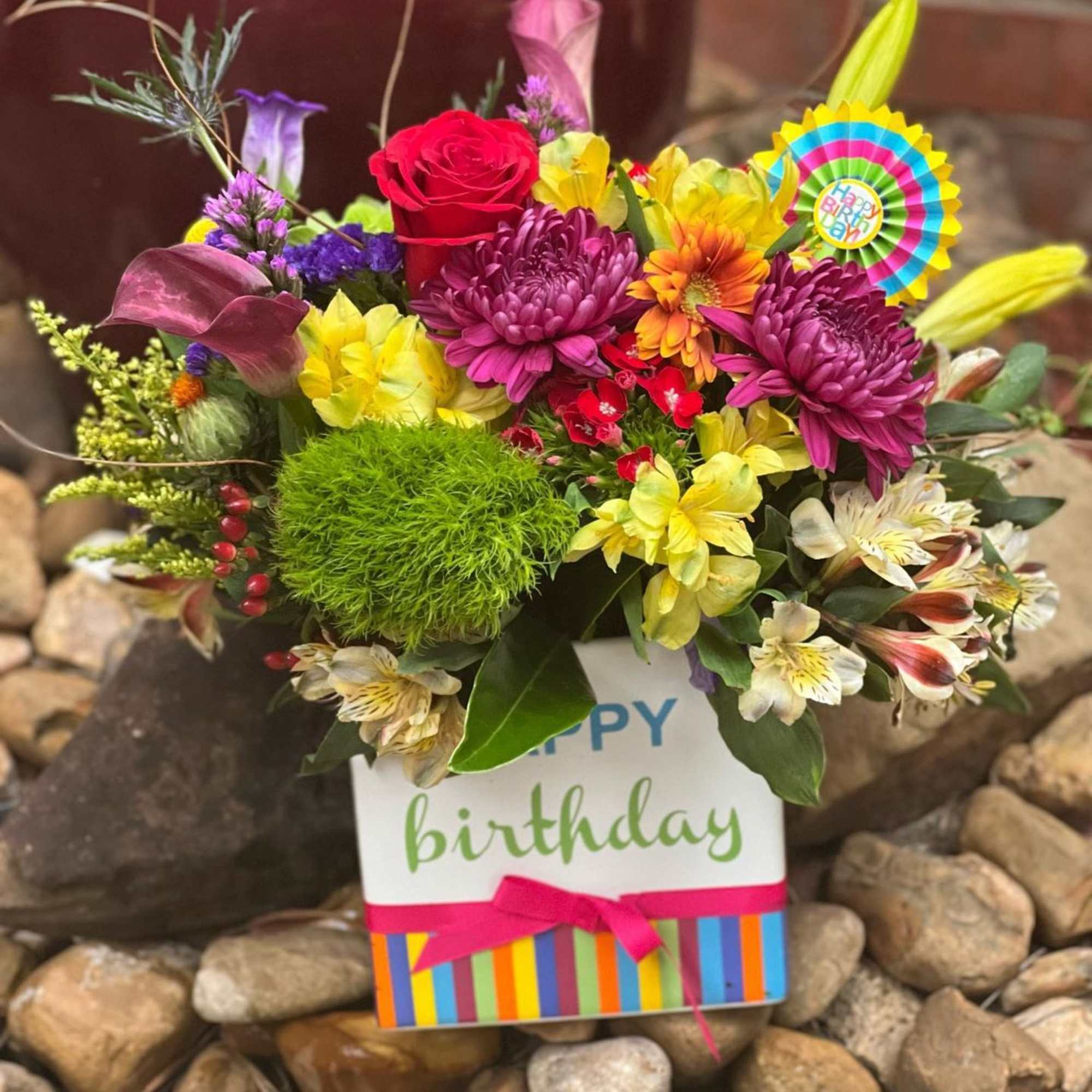 Colorful birthday flower arrangement in a gift bag with a ribbon