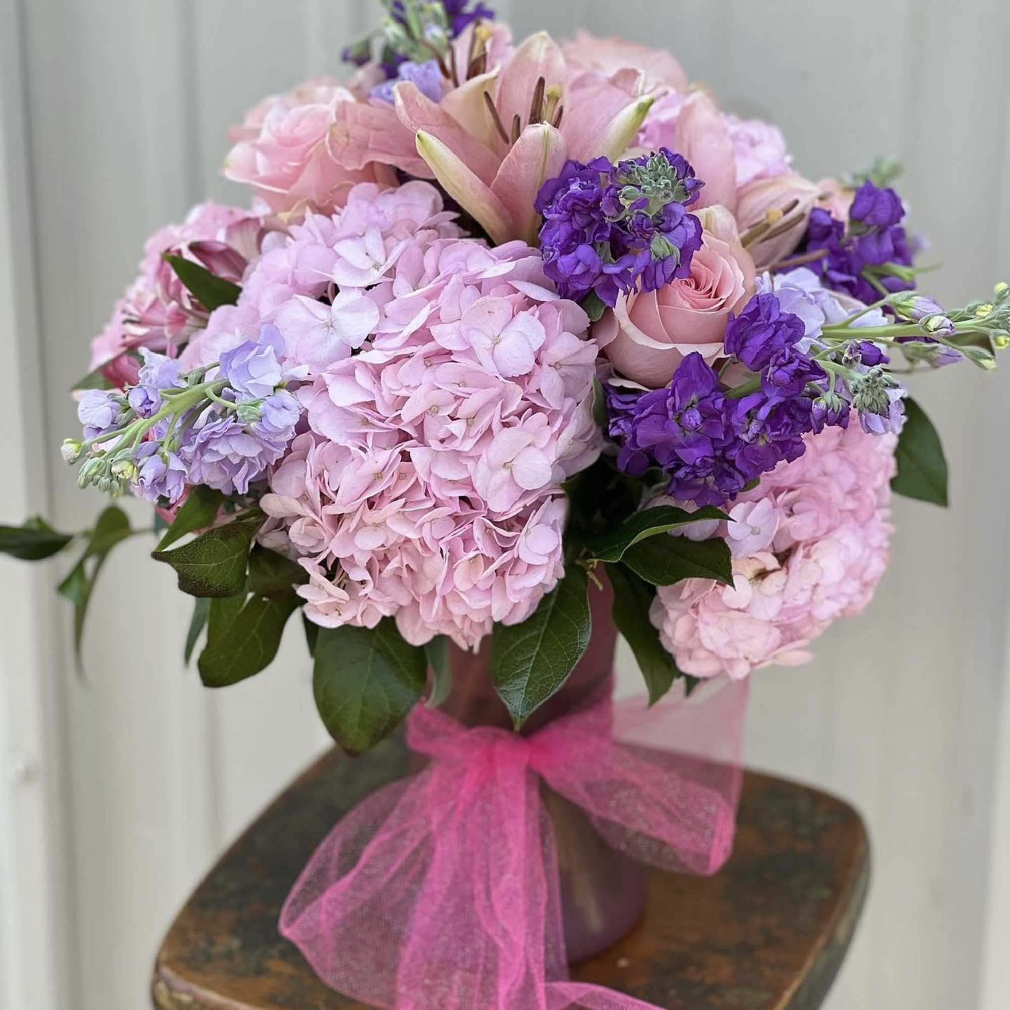 Pink and purple bouquet in a vase with a pink ribbon