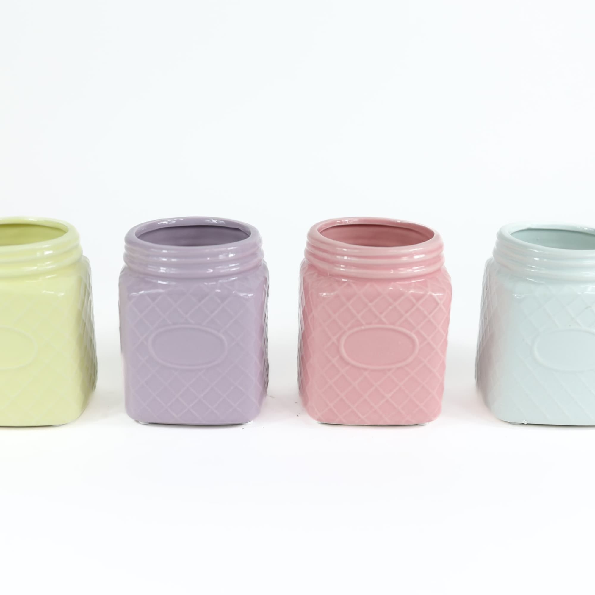 Four pastel square glass jars on a white background