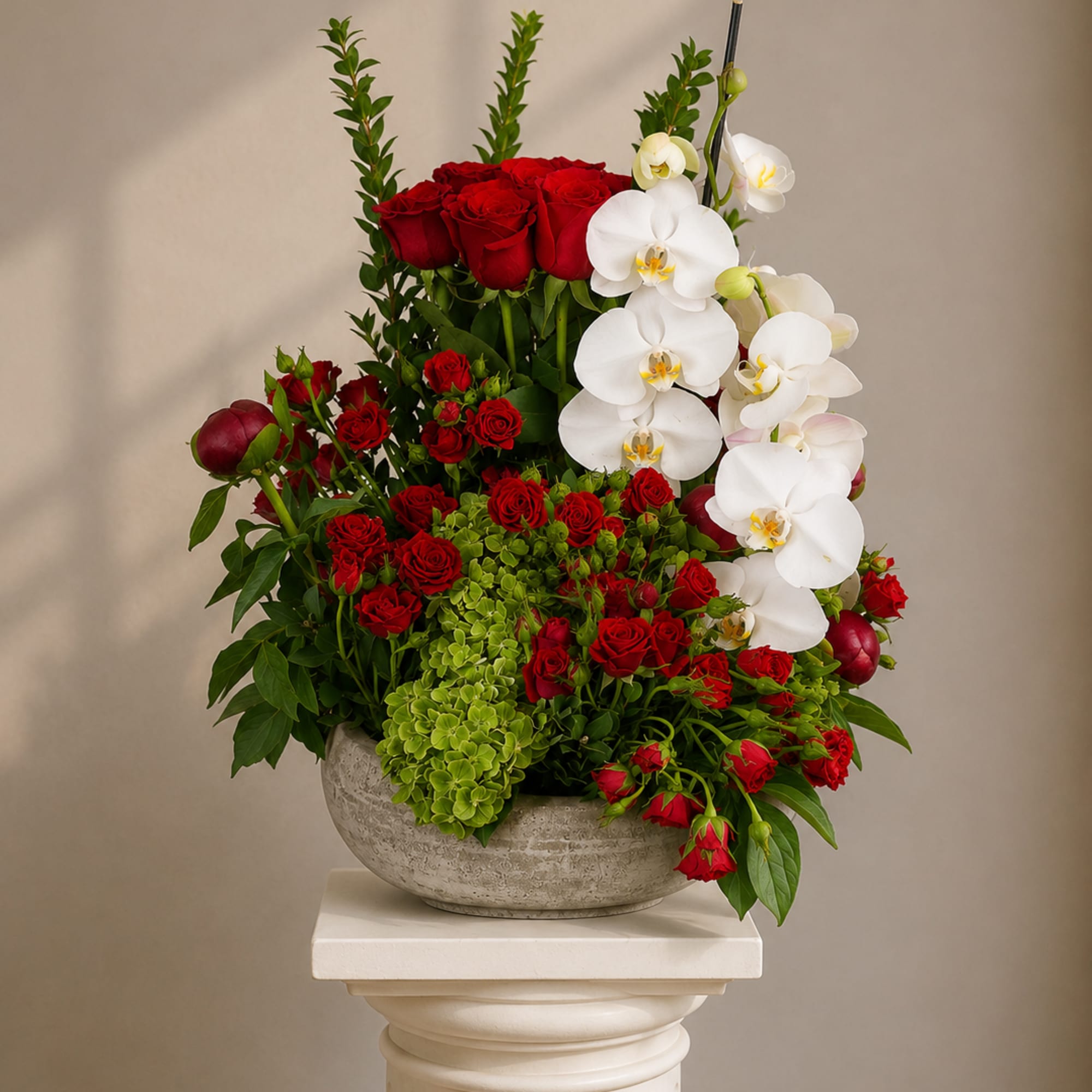 Deep clusters of deep red roses meet cascading white Phalaenopsis orchids in