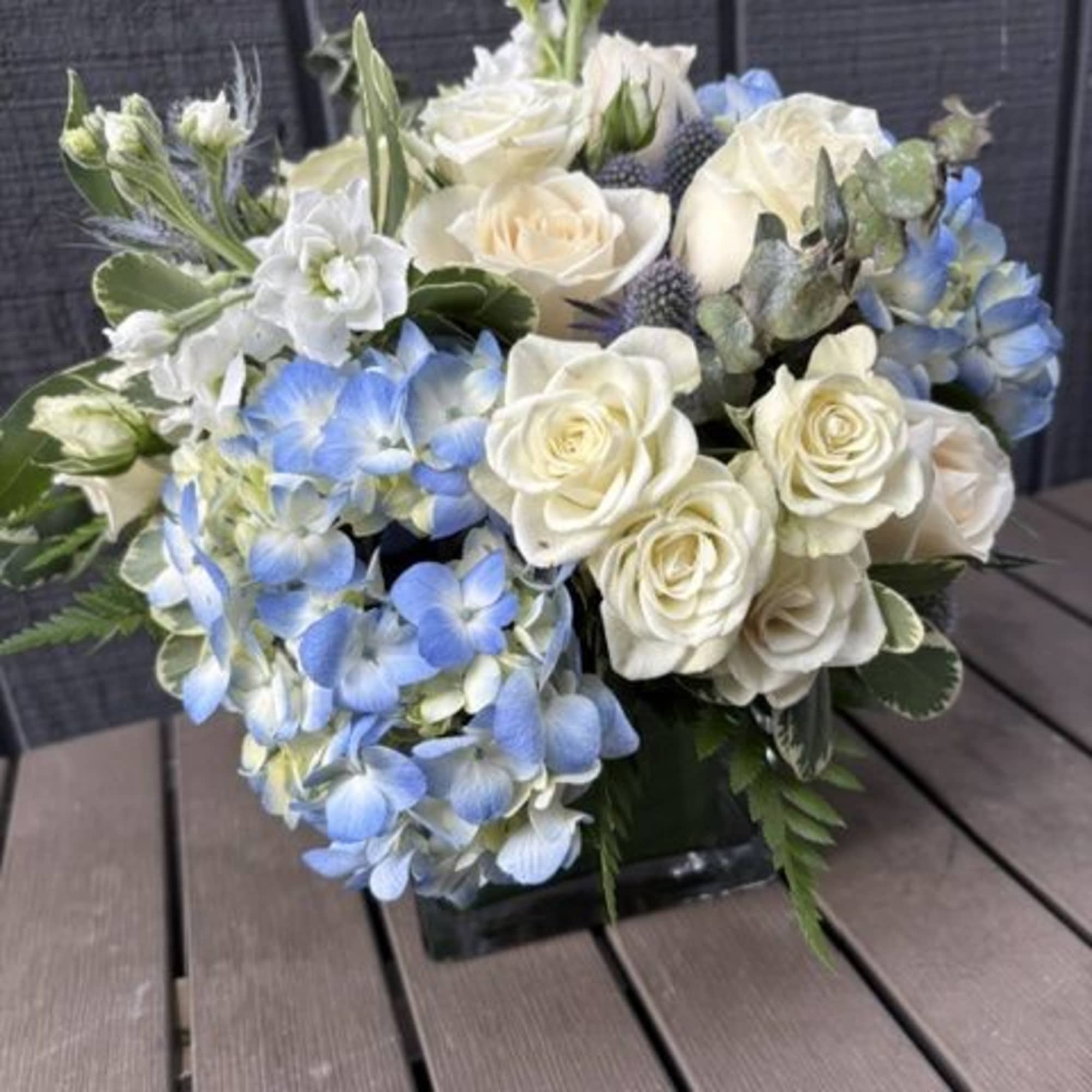 
Creamy white roses and soft blue hydrangeas form a cool, airy centerpiece