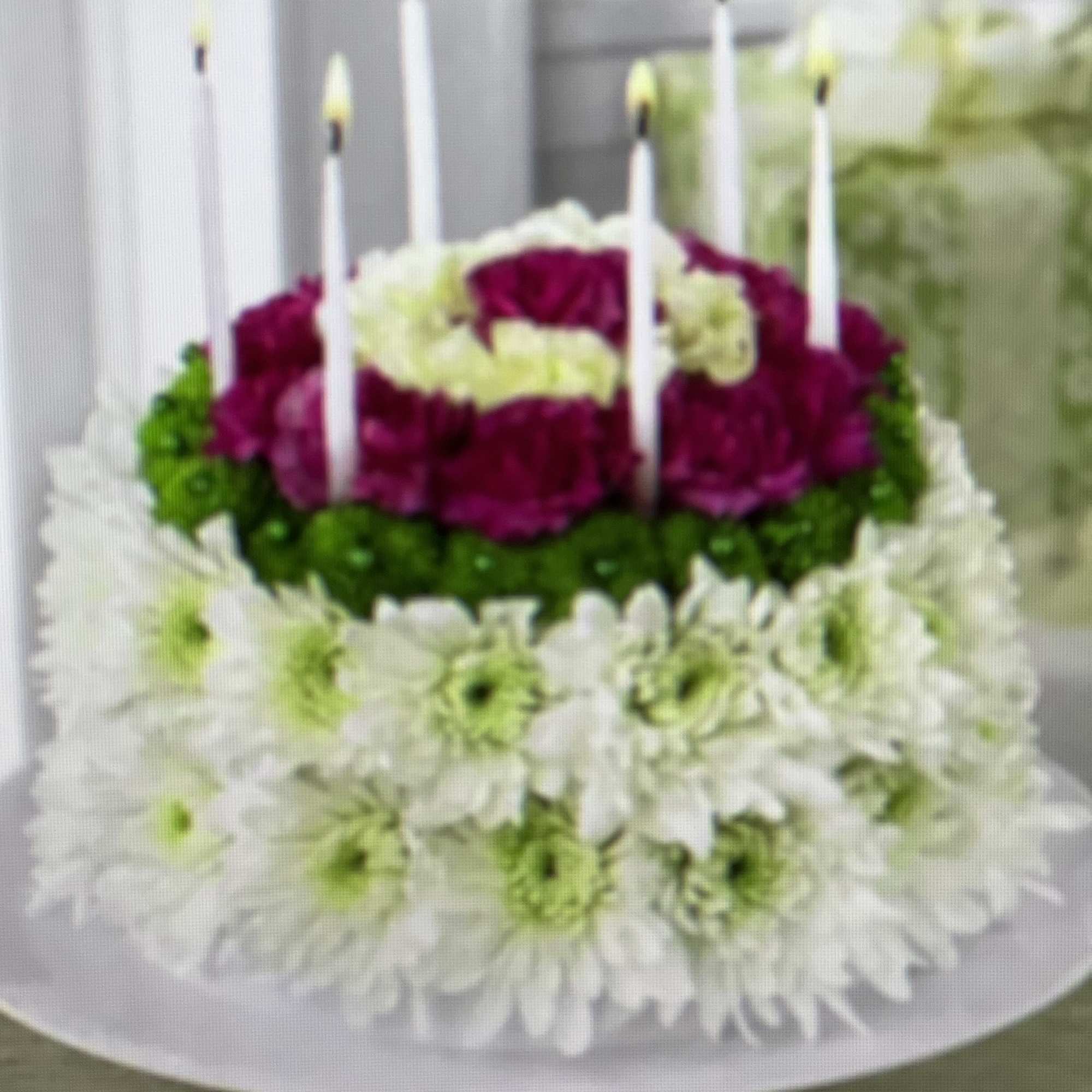 Tiered floral cake with white daisies and magenta blooms, topped with candles
