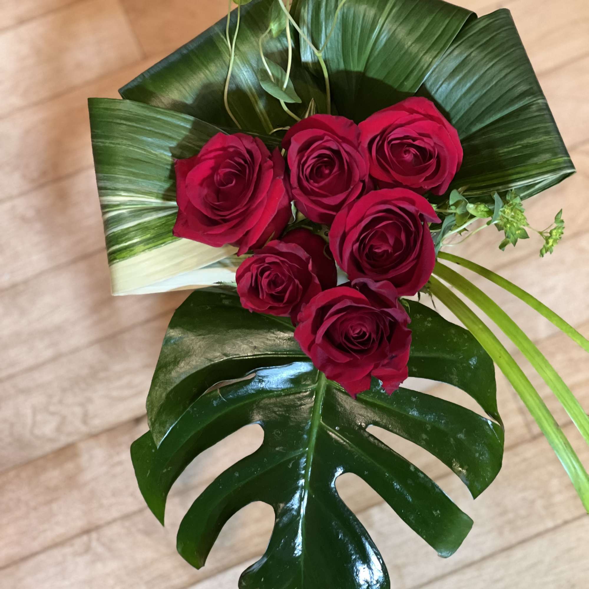Bouquet of red roses with large tropical leaves