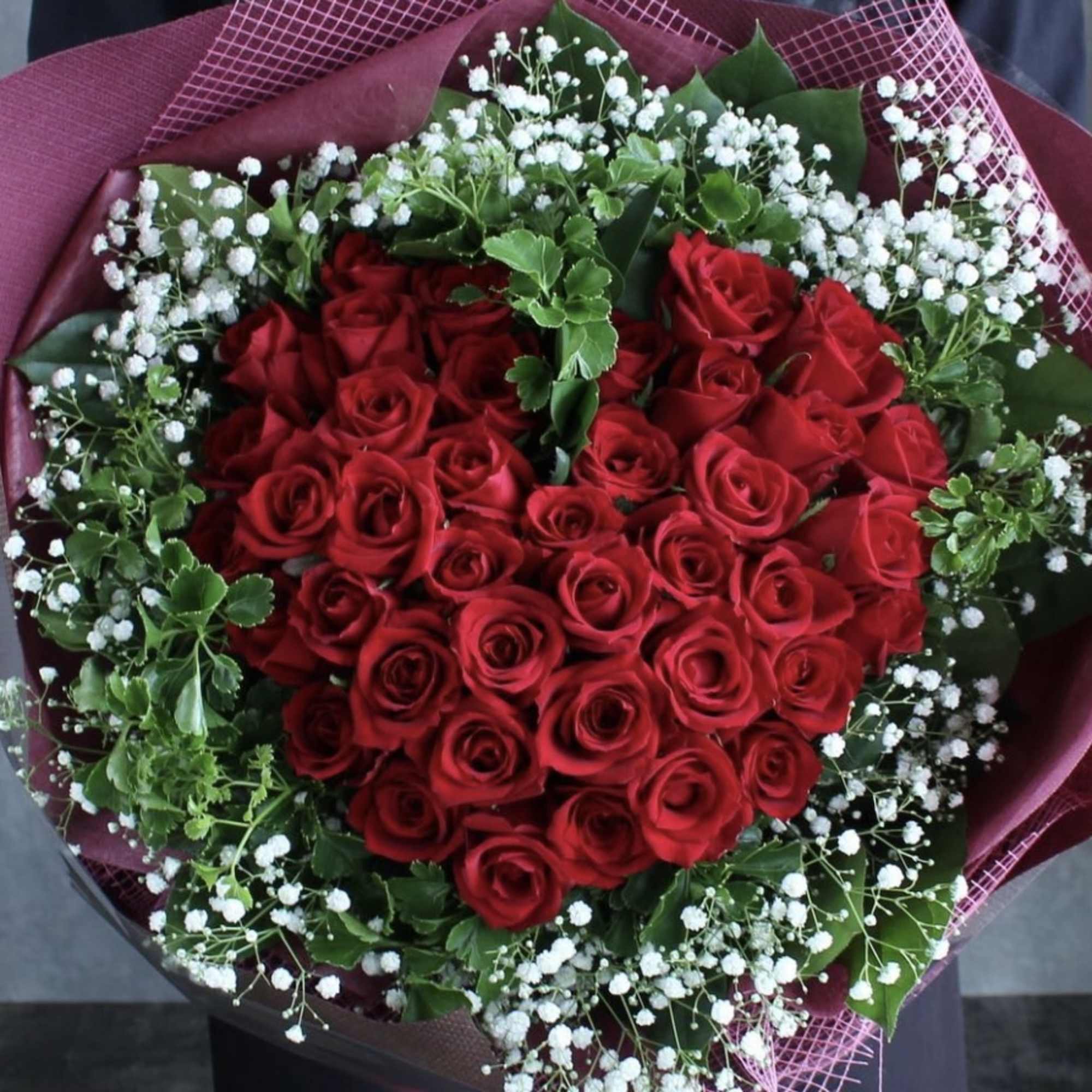 Heart-shaped bouquet of red roses with white baby's breath