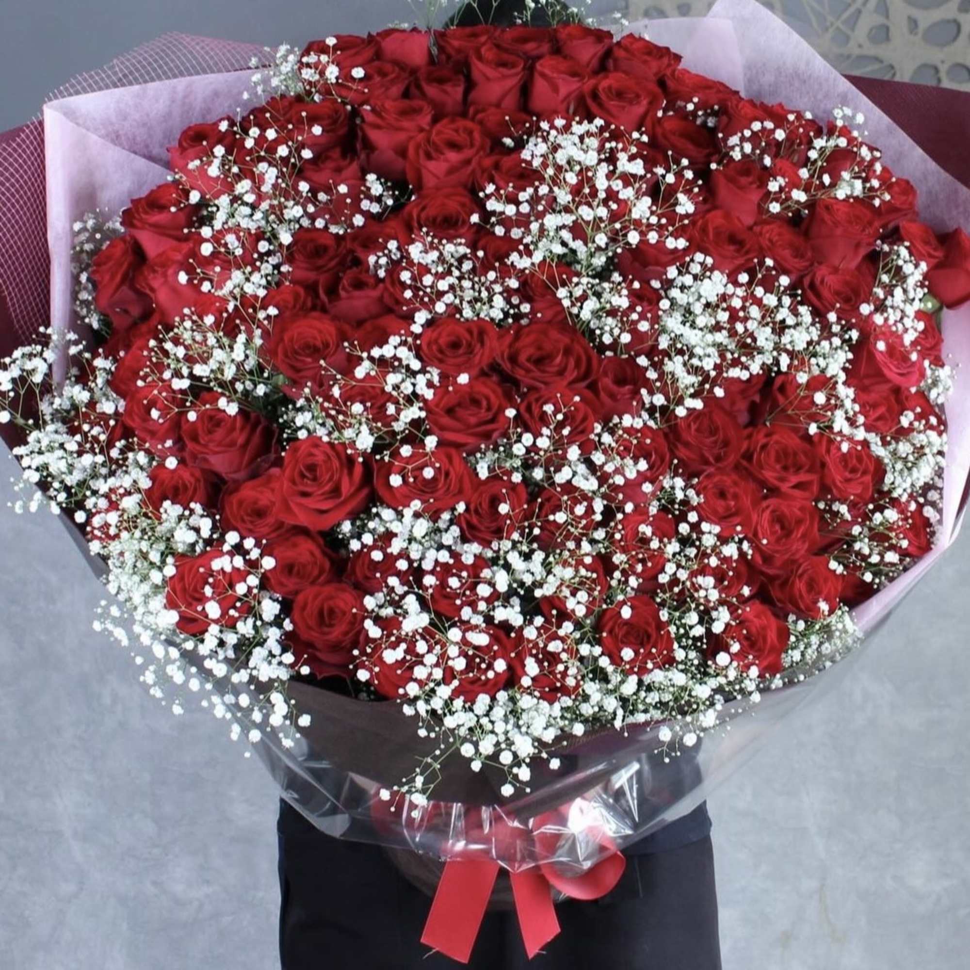 Large bouquet of red roses with white baby's breath in pink wrapping