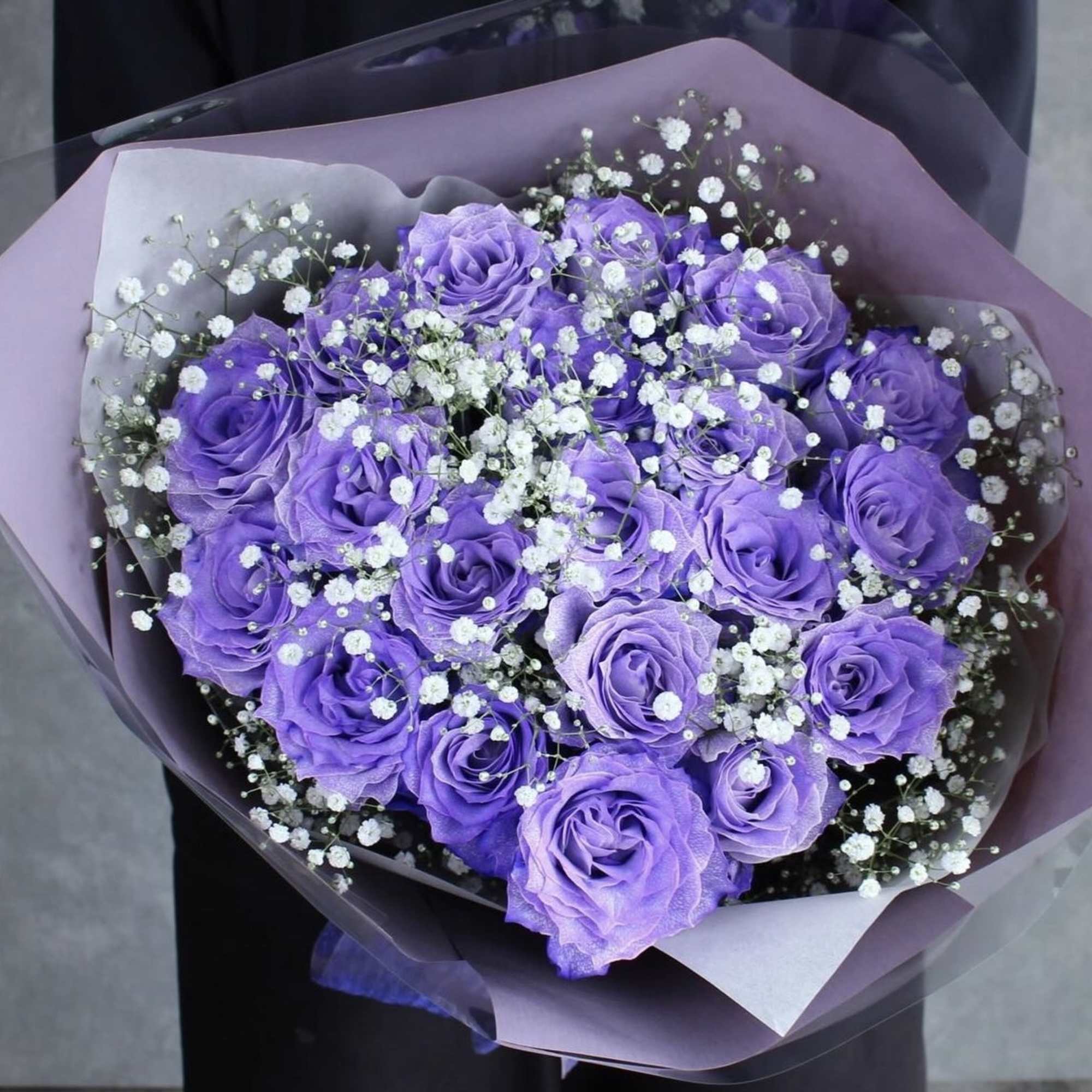 Bouquet of purple roses with white baby's breath in lavender wrap