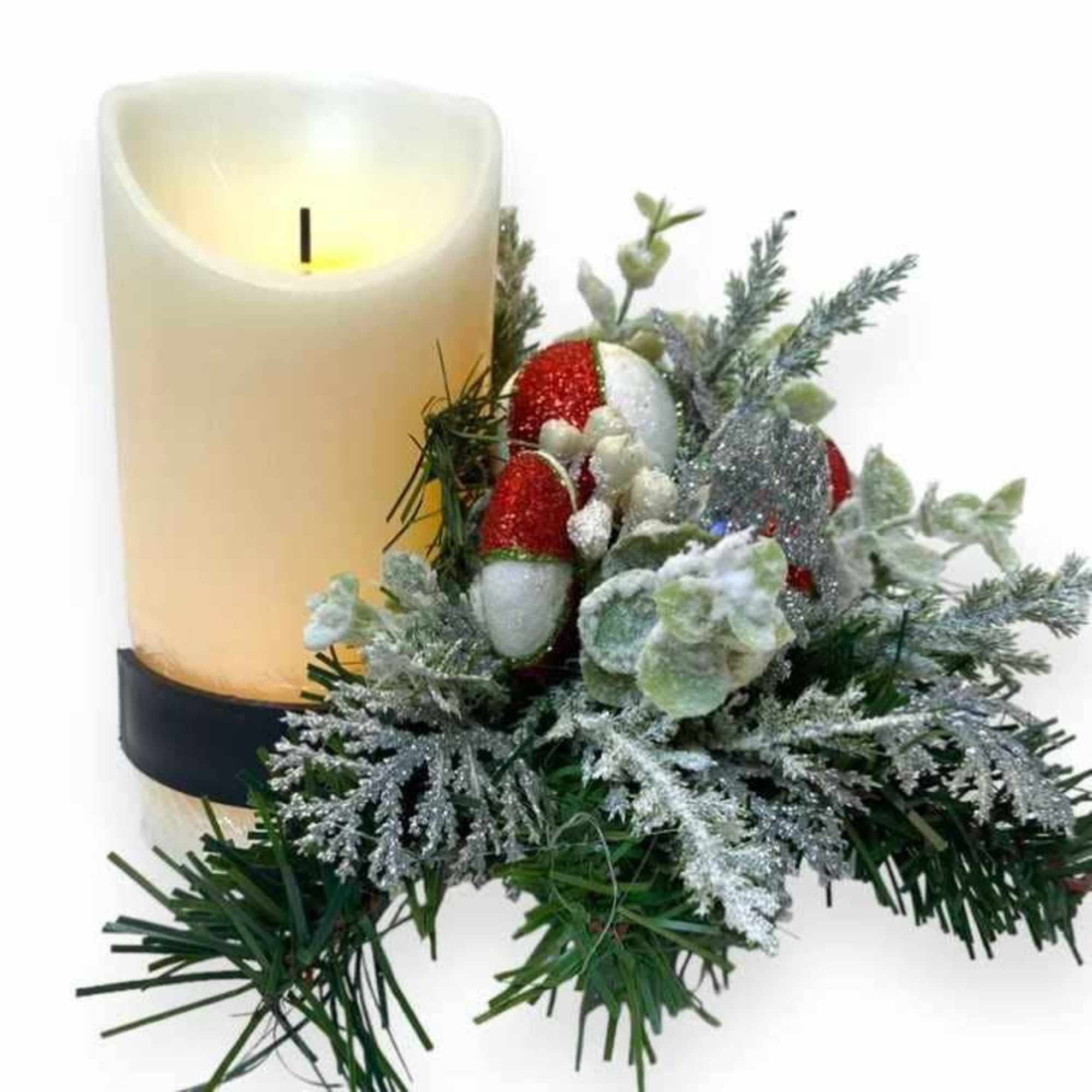 Lit pillar candle with a Christmas greenery and berry arrangement