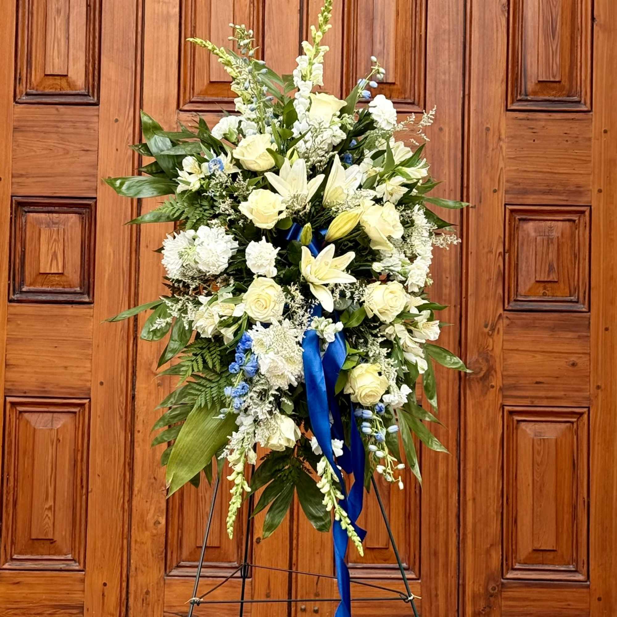 The White and Blue Standing Spray is a peaceful and elegant tribute