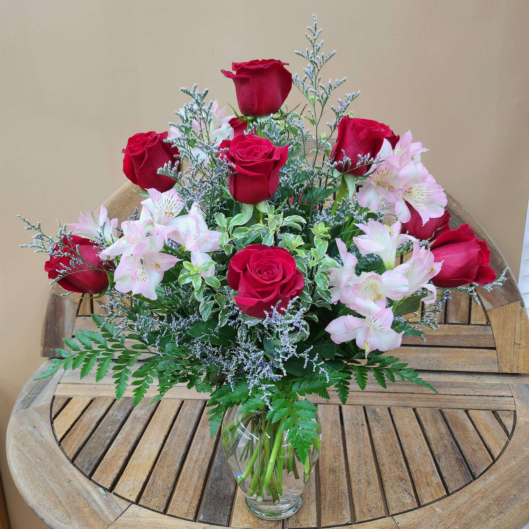 Bouquet of red roses and pale pink flowers in a clear glass vase