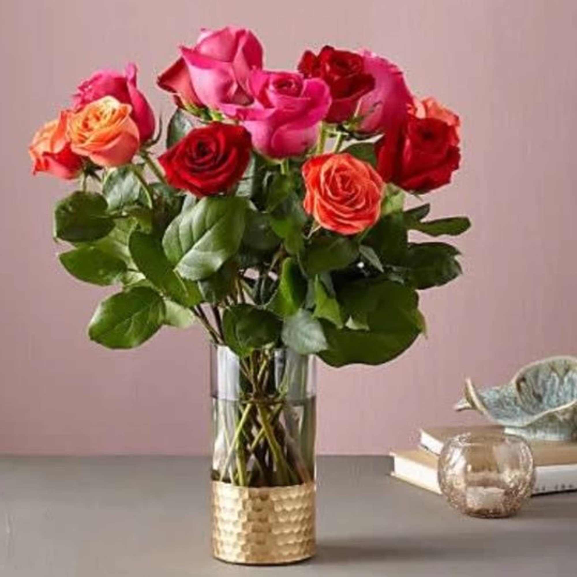 Mixed roses in a clear glass vase with a gold-textured base