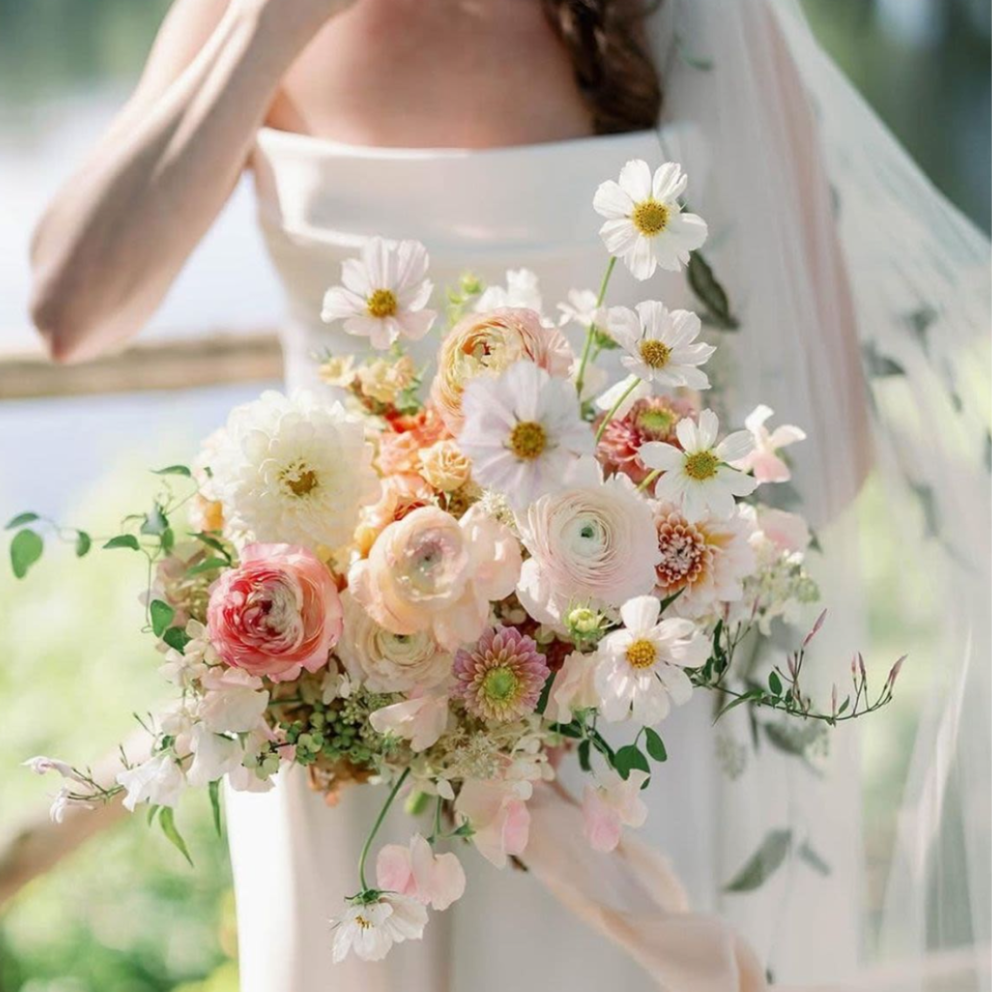 Bride holding a pastel bouquet with white daisies and blush blooms