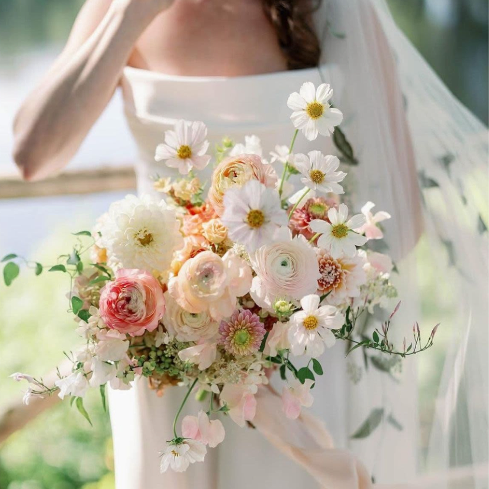 Bride holding a pastel bouquet with white daisies and blush ranunculus