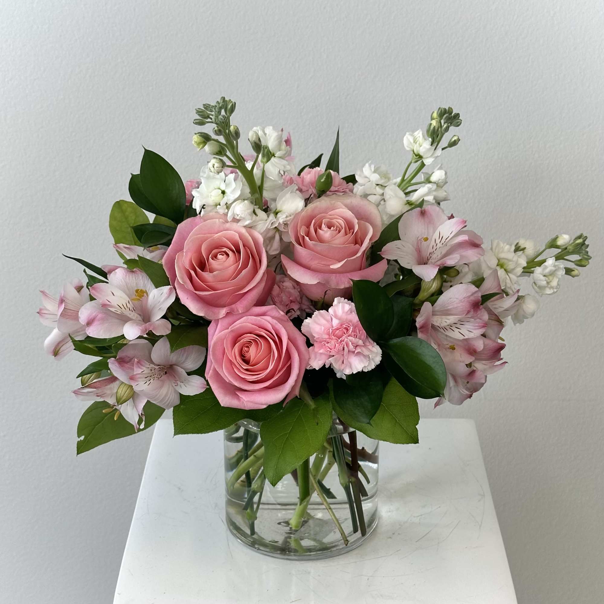 Pink roses and white flowers arranged in a clear glass vase
