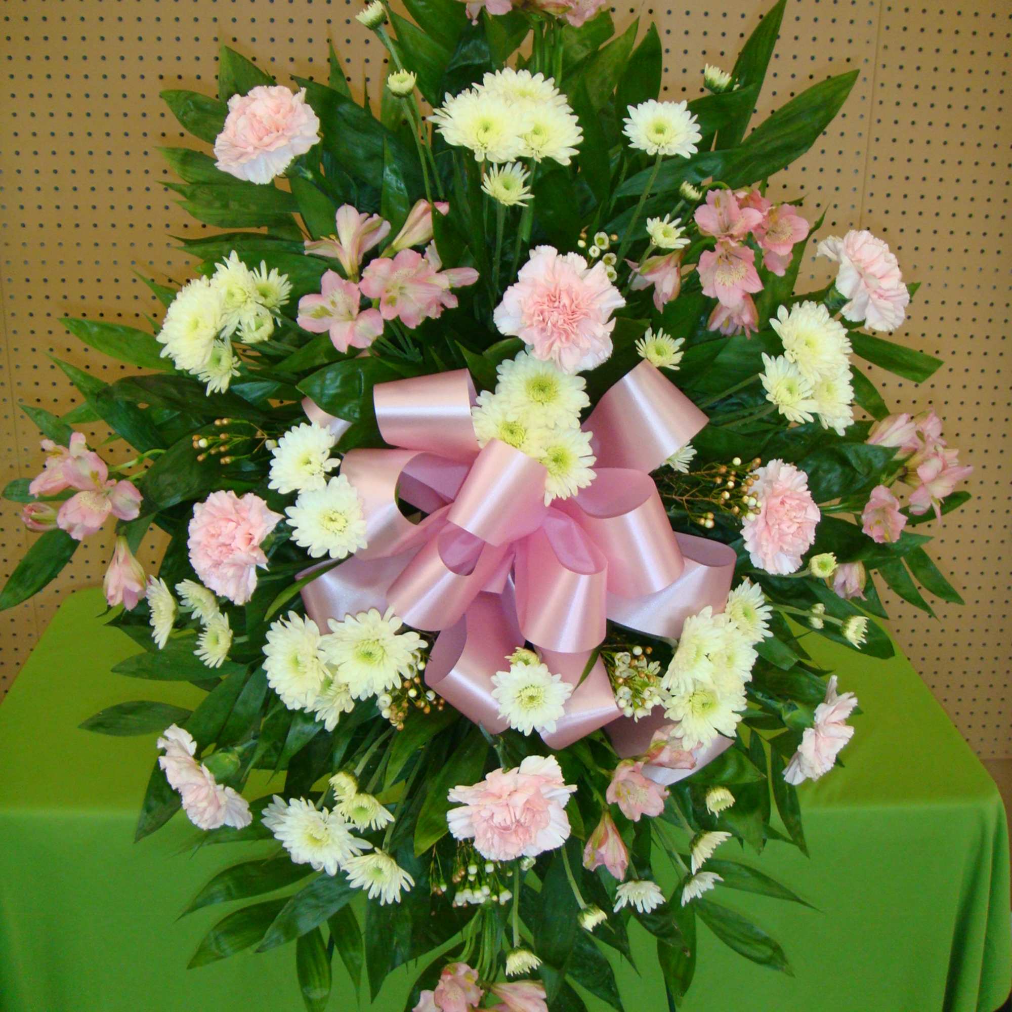 Standing floral spray with pink and white flowers and a large pink ribbon