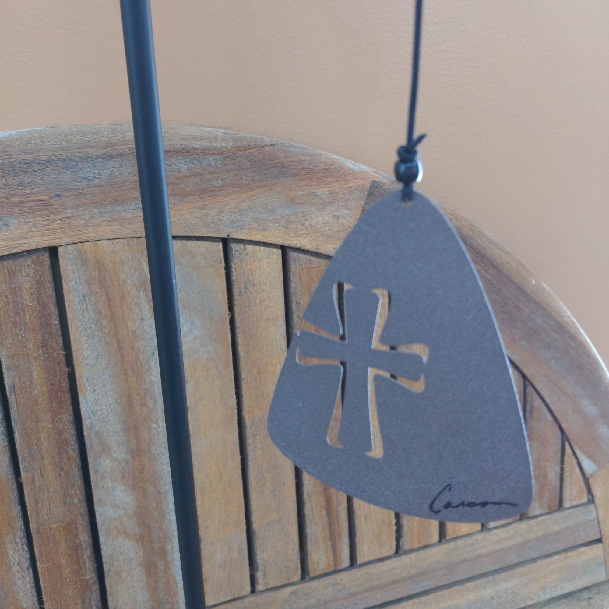 Black hanging ornament with a cutout cross on a wooden chair