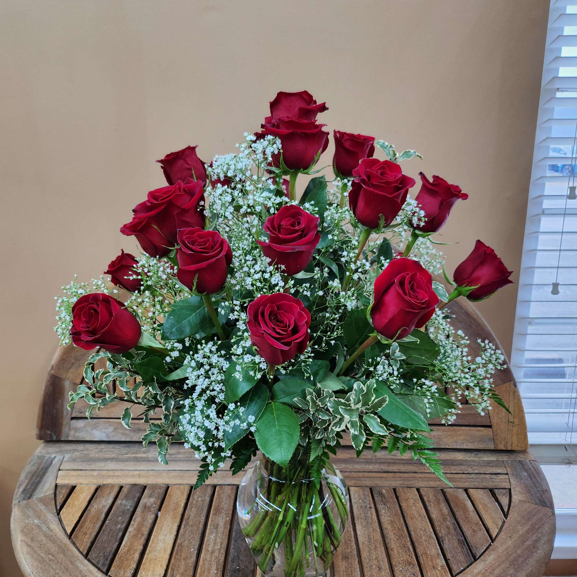 Red roses arranged in a clear glass vase with white filler flowers