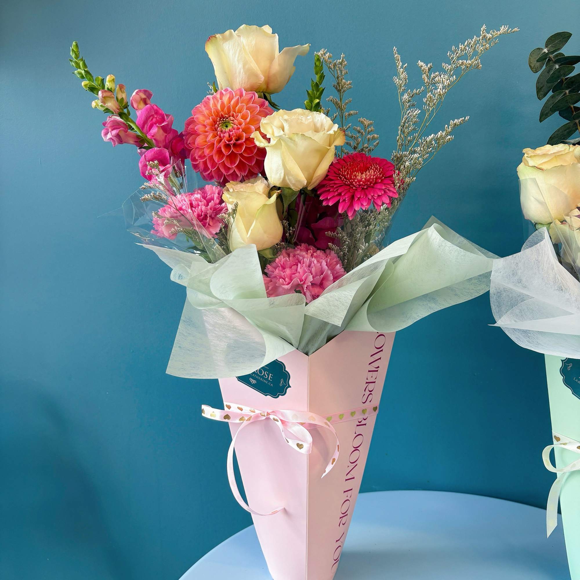 Pink and cream bouquet with roses, dahlias, and carnations in a pastel wrap