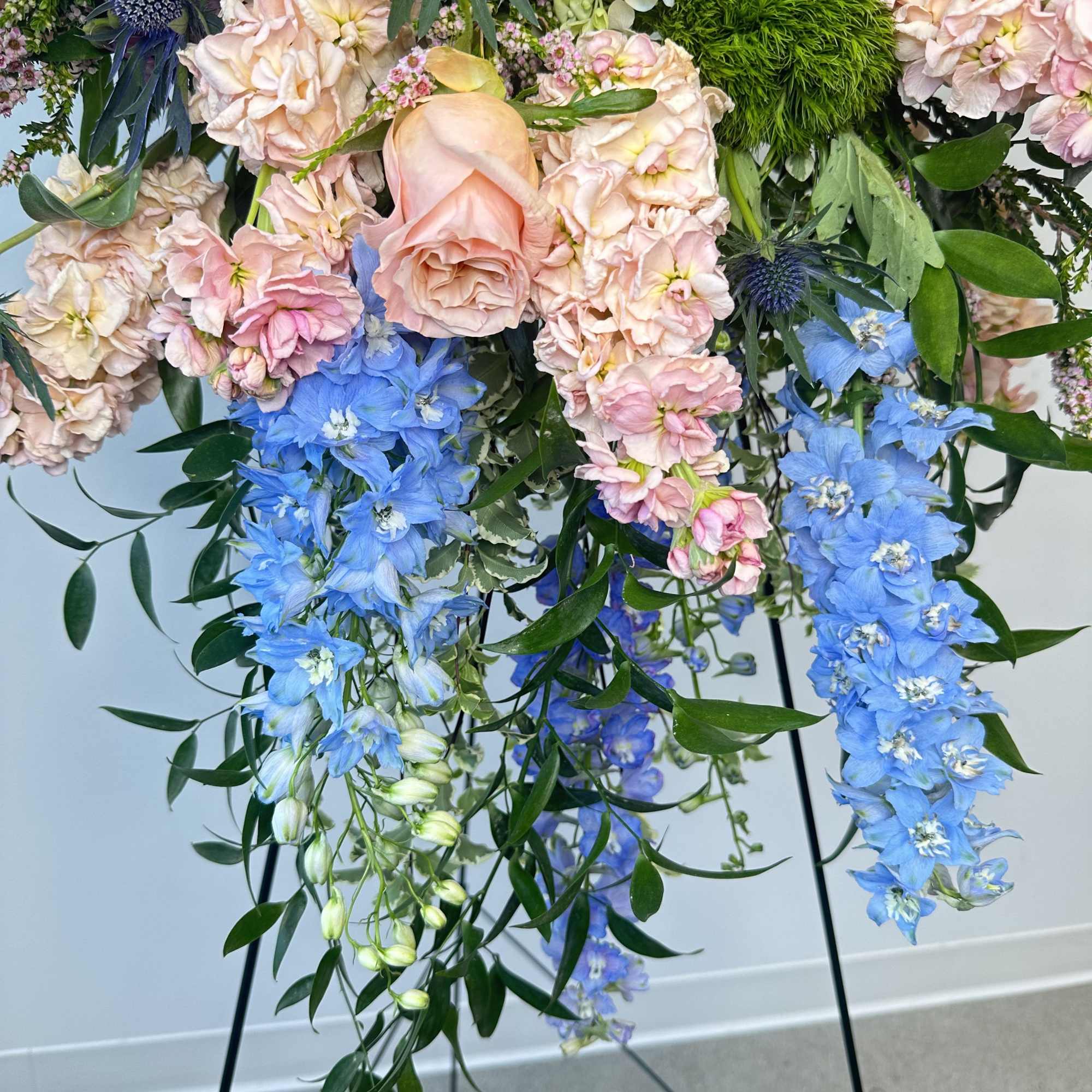 Pastel floral arrangement with blue and blush blooms on a stand