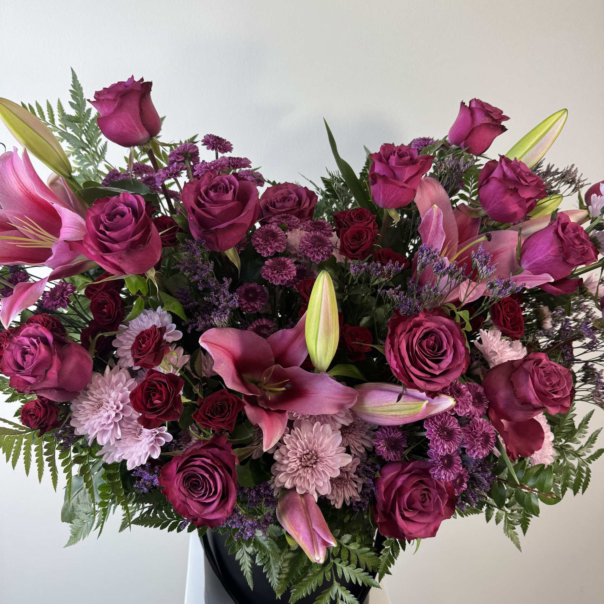 Large bouquet of magenta roses and pink lilies in a black vase