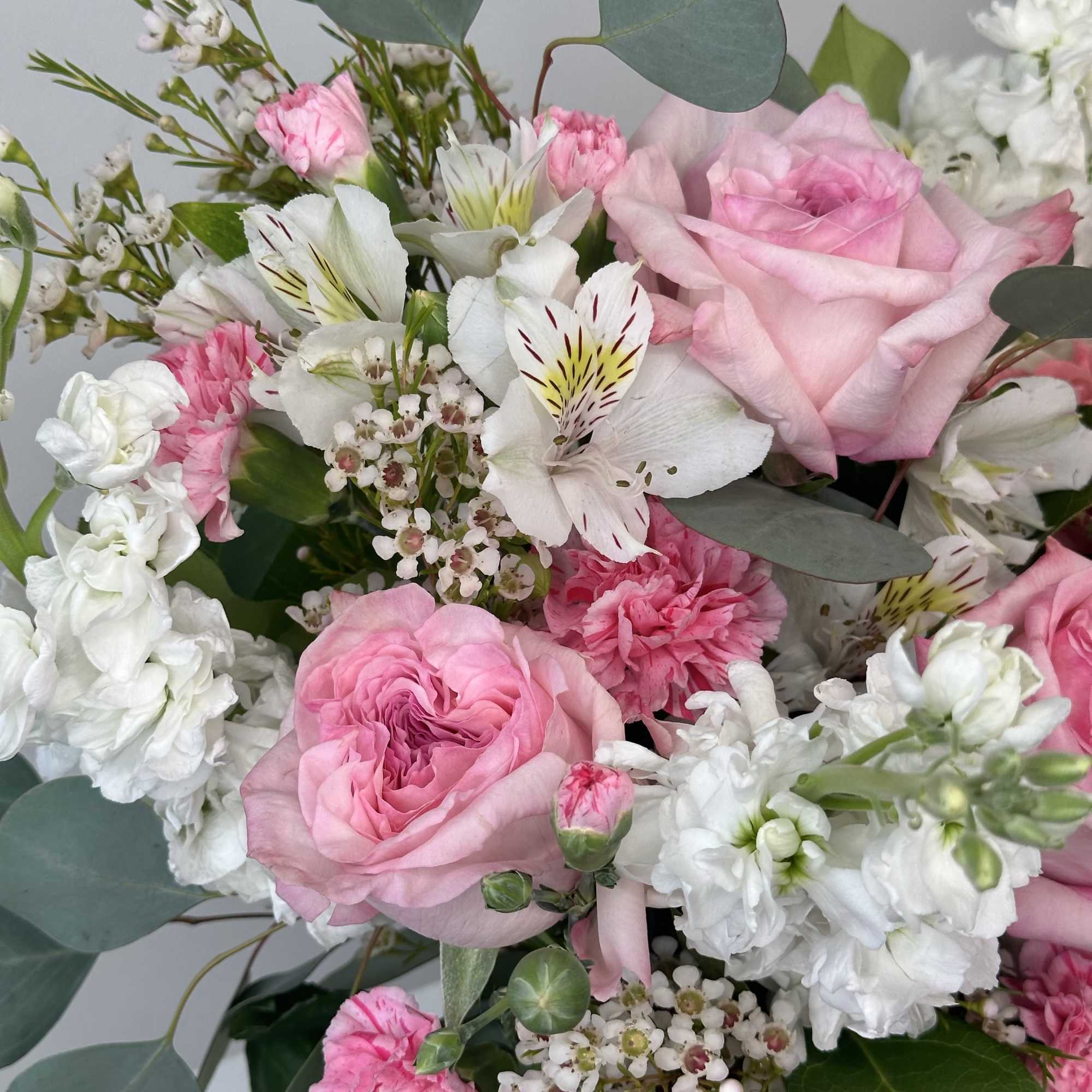 Pink roses and white flowers arranged with eucalyptus