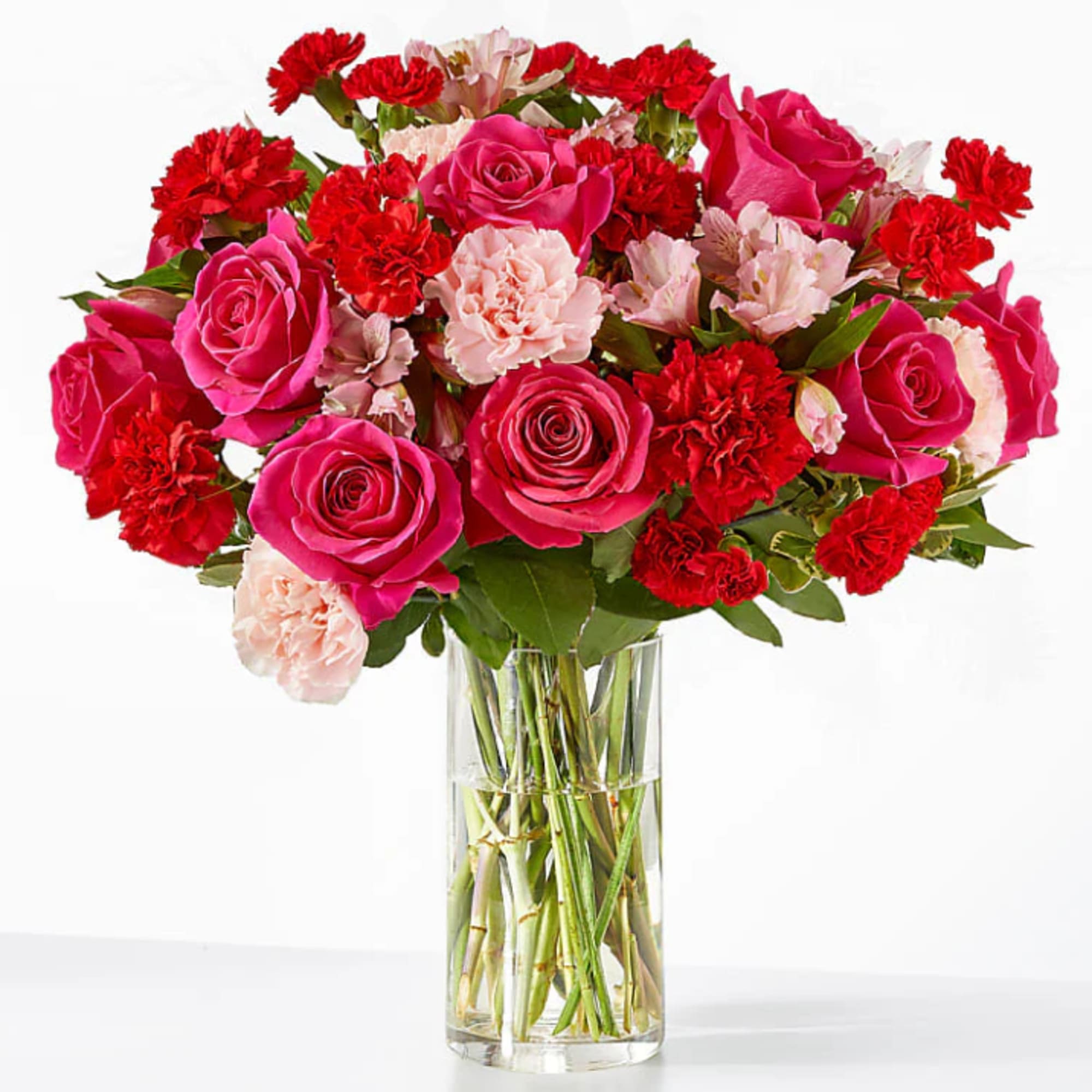 Bouquet of pink roses, red carnations, and pale pink flowers in a clear glass vase