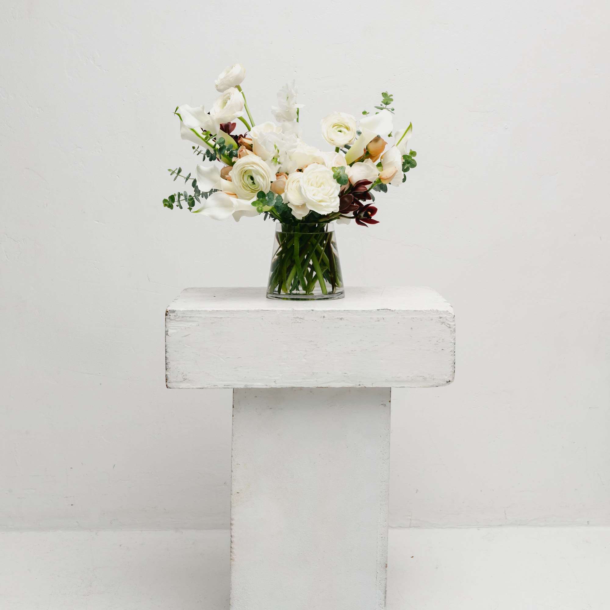 White floral arrangement in a clear glass vase on a pedestal